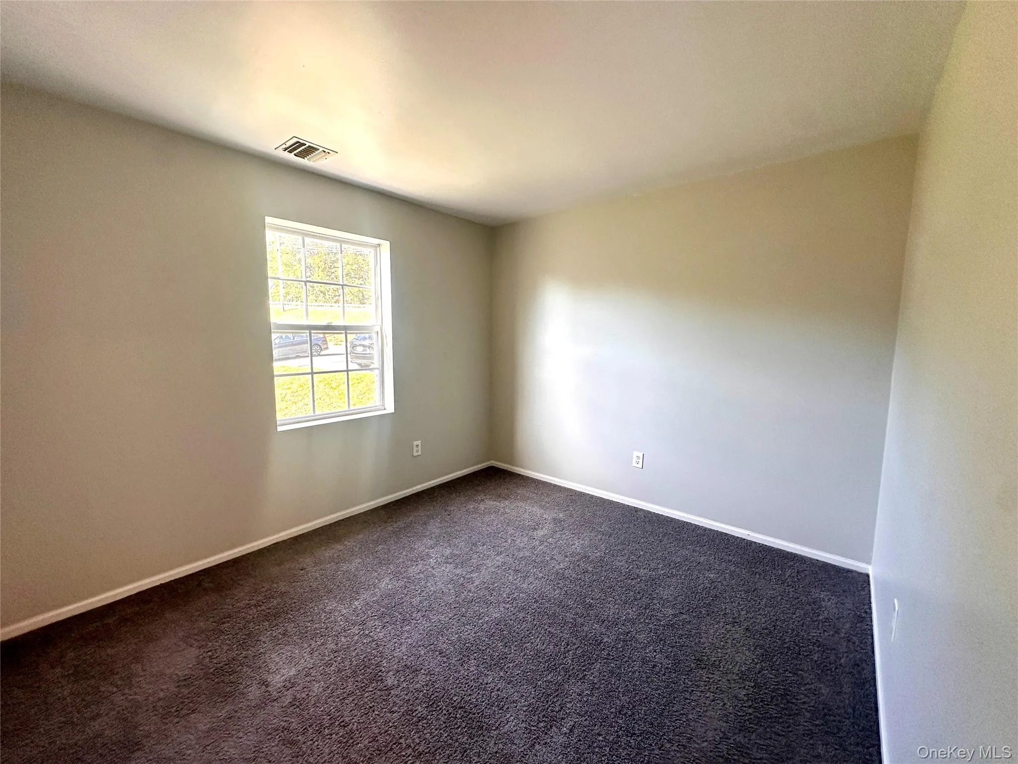 Unfurnished room with dark carpet and baseboards Unfurnished room with dark carpet and baseboards
