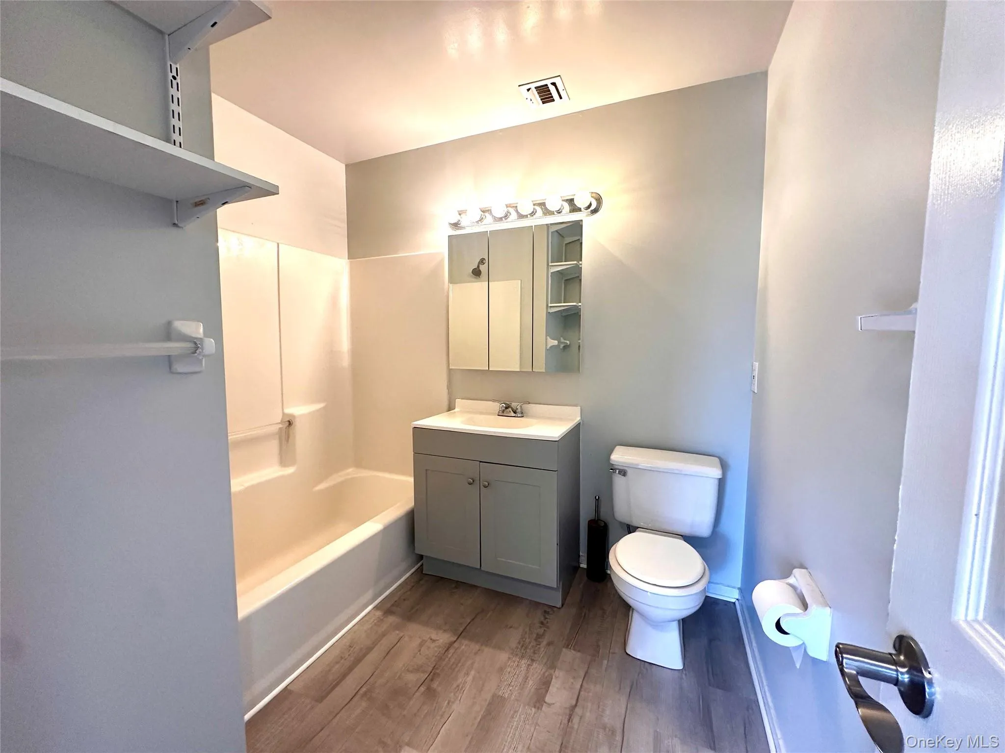 Full bath with vanity, dark wood-style floors, and shower / bathtub combination Full bath with vanity, dark wood-style floors, and shower / bathtub combination