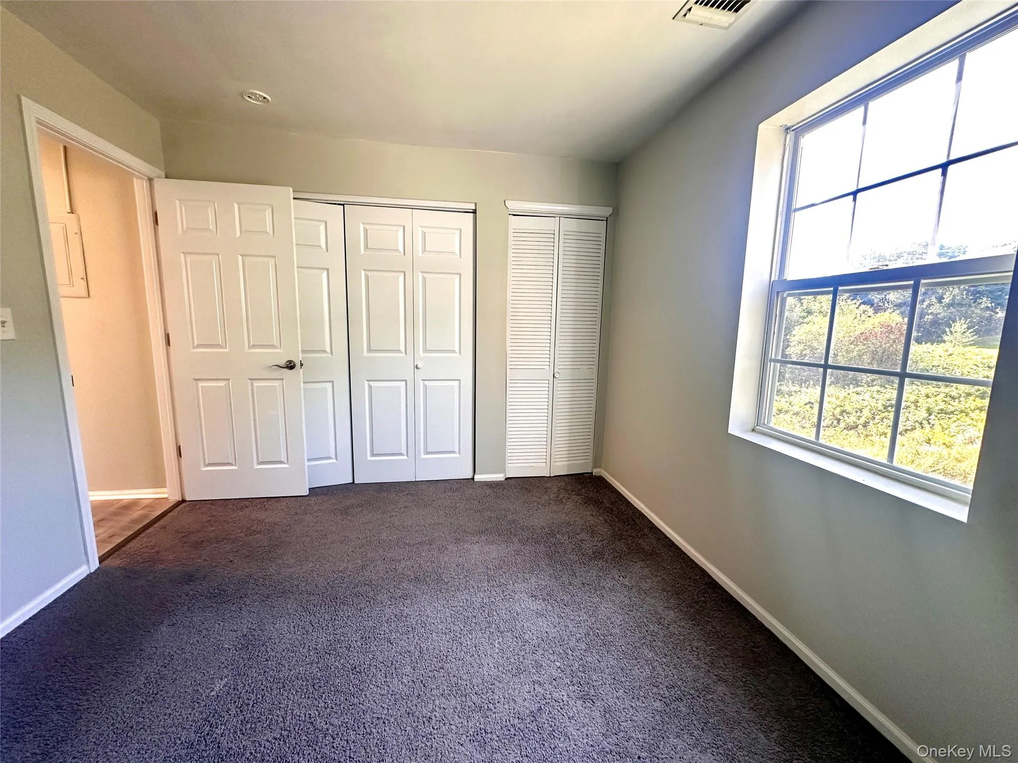 Unfurnished bedroom featuring multiple closets and dark carpet Unfurnished bedroom featuring multiple closets and dark carpet
