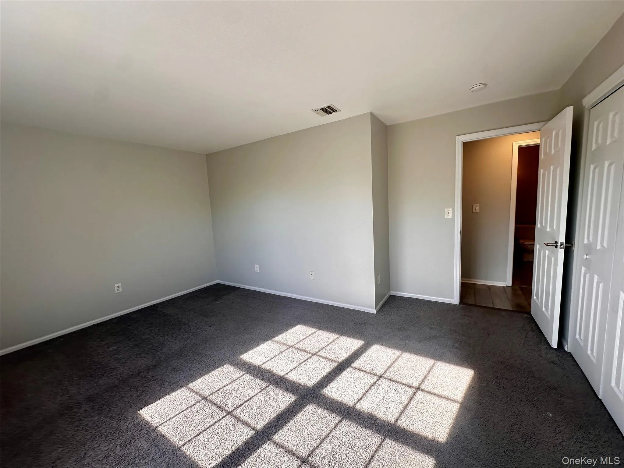 Empty room featuring dark carpet and baseboards Empty room featuring dark carpet and baseboards