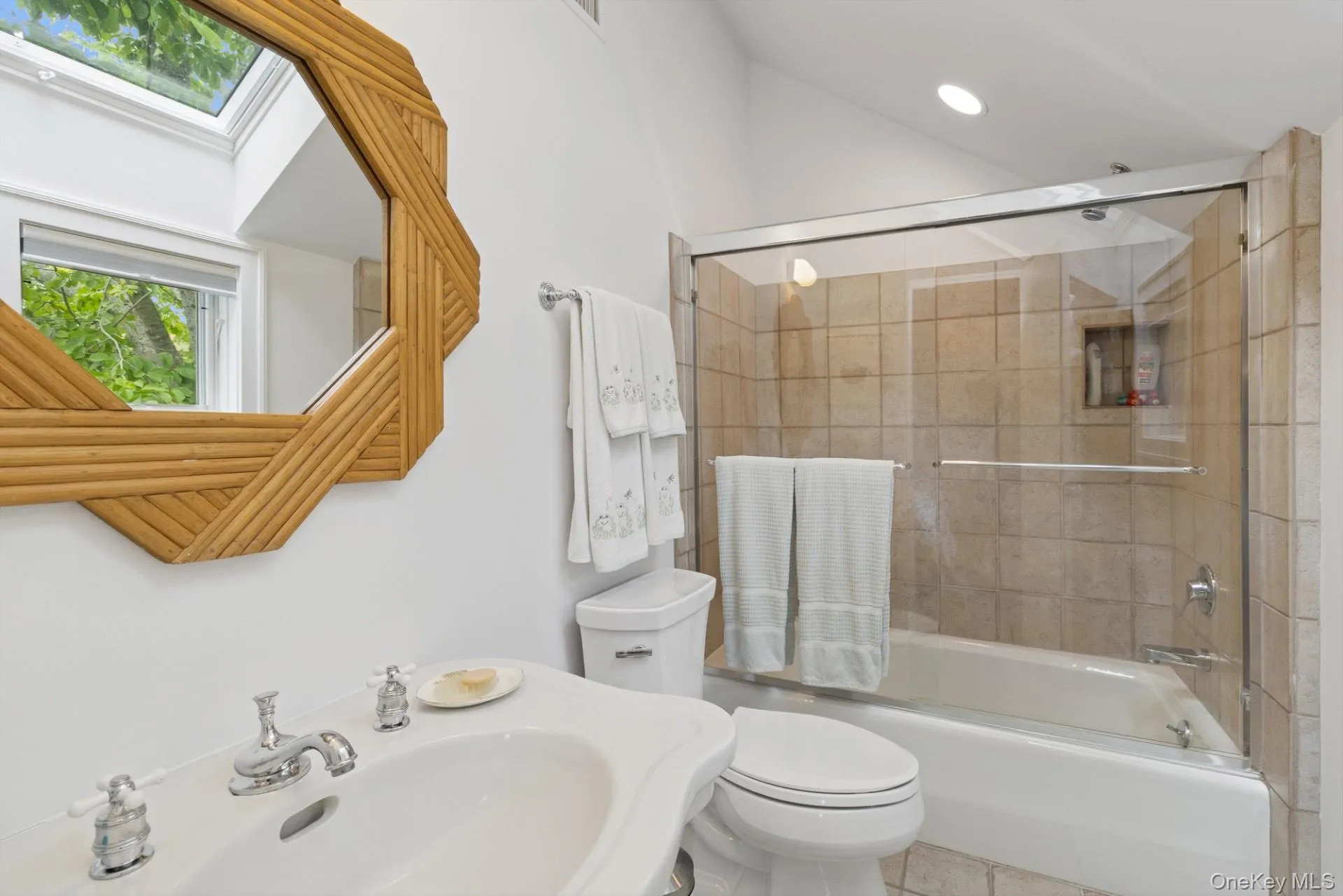 Bathroom featuring bath / shower combo with glass door, a skylight, and tile patterned flooring Bathroom featuring bath / shower combo with glass door, a skylight, and tile patterned flooring