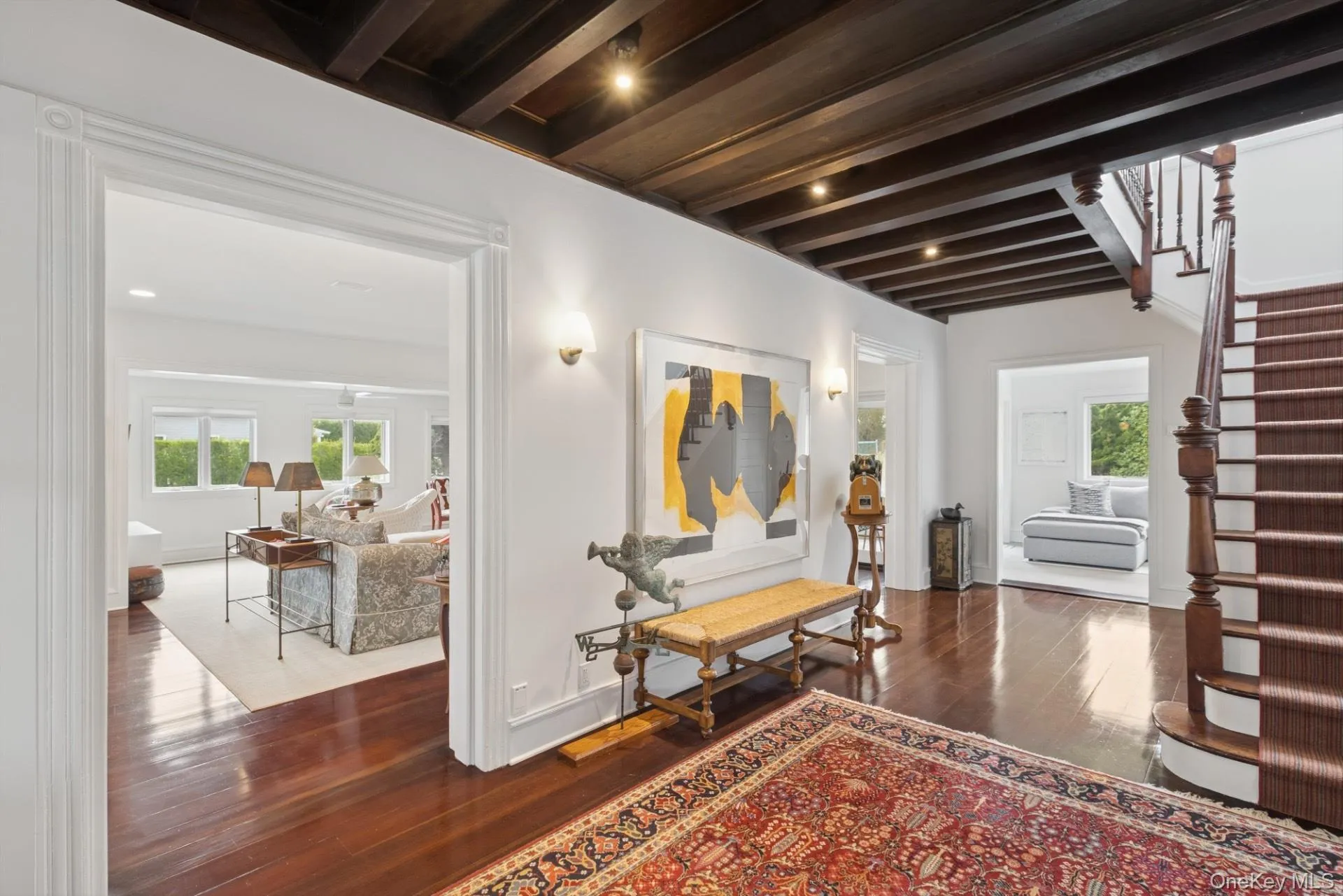 Hallway featuring beam ceiling, dark wood-style flooring, stairway, and healthy amount of natural light Hallway featuring beam ceiling, dark wood-style flooring, stairway, and healthy amount of natural light