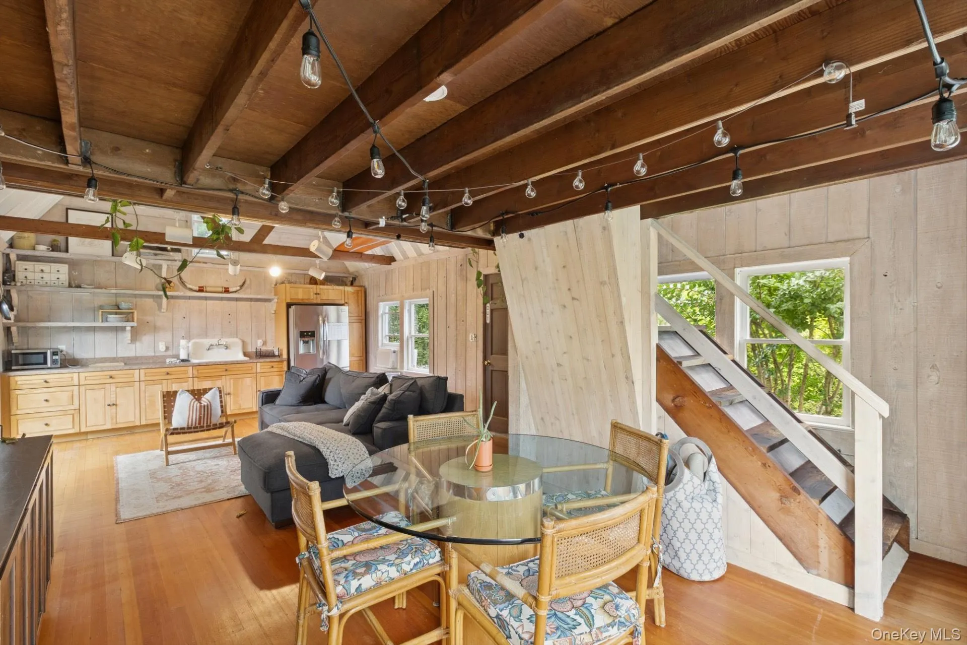 Dining room featuring rail lighting, wood walls, beamed ceiling, light wood finished floors, and stairway Dining room featuring rail lighting, wood walls, beamed ceiling, light wood finished floors, and stairway