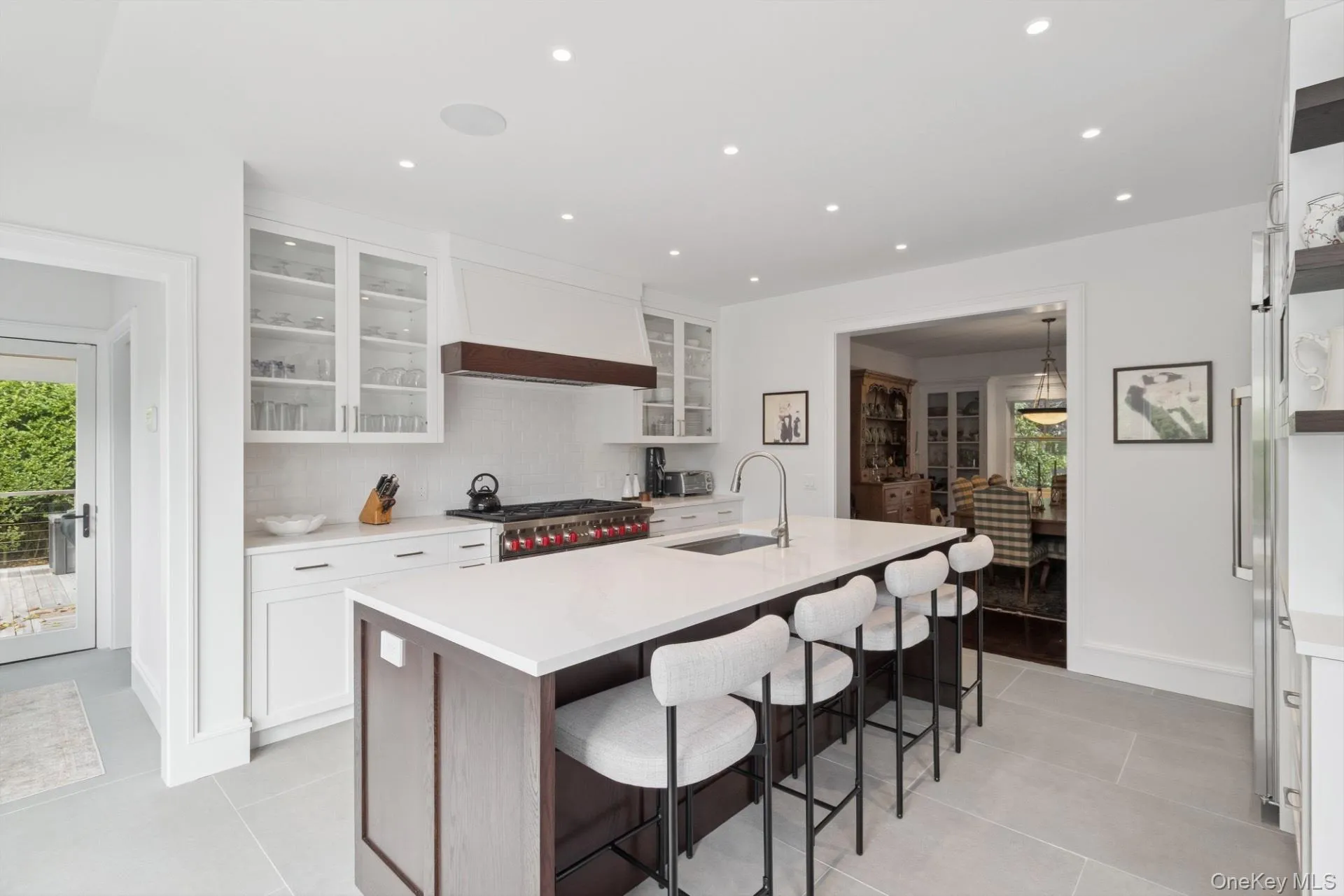 Kitchen with plenty of natural light, white cabinetry, a breakfast bar, glass insert cabinets, and recessed lighting Kitchen with plenty of natural light, white cabinetry, a breakfast bar, glass insert cabinets, and recessed lighting
