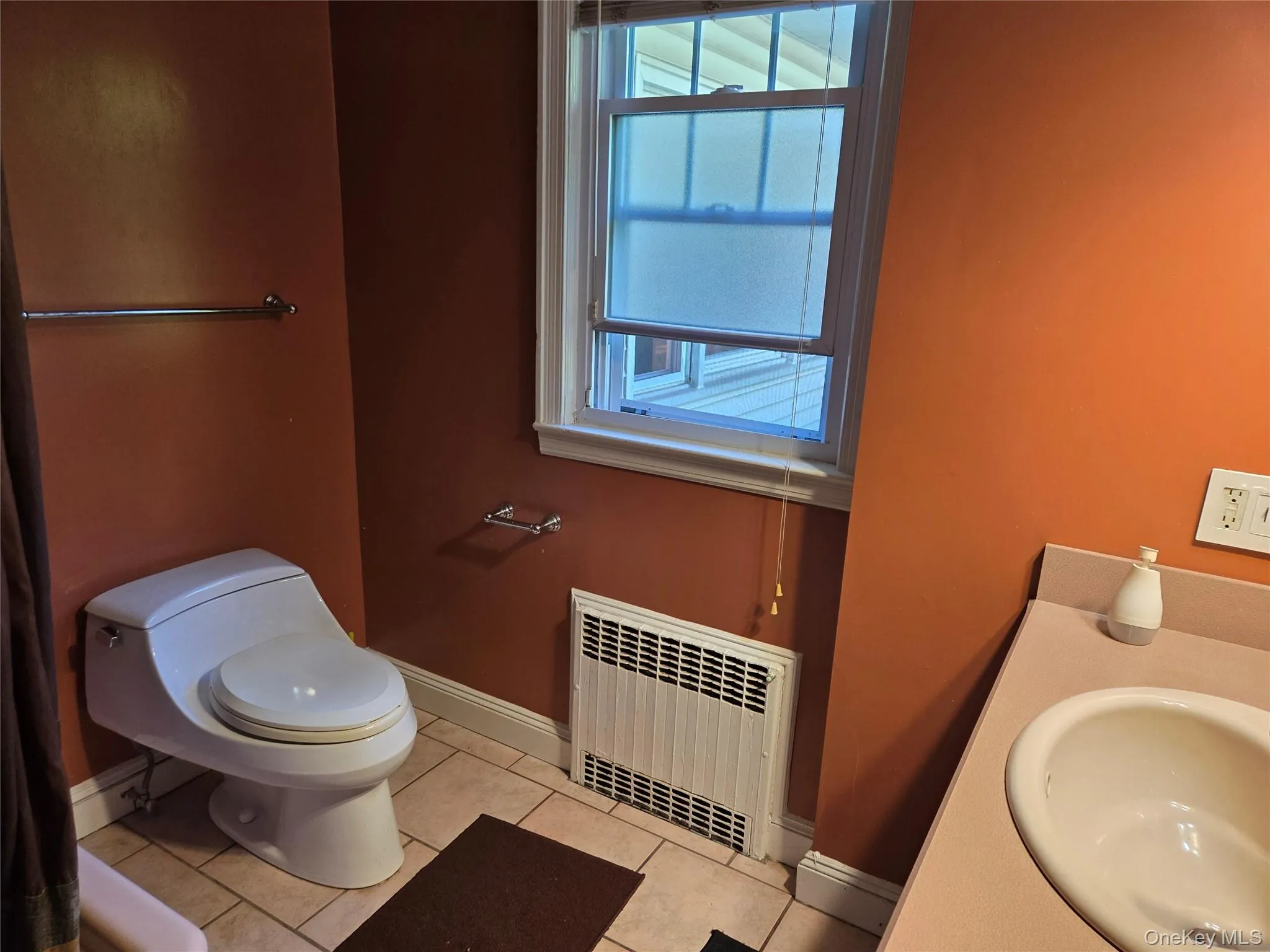 Bathroom featuring radiator heating unit, light tile patterned floors, plenty of natural light, and vanity Bathroom featuring radiator heating unit, light tile patterned floors, plenty of natural light, and vanity