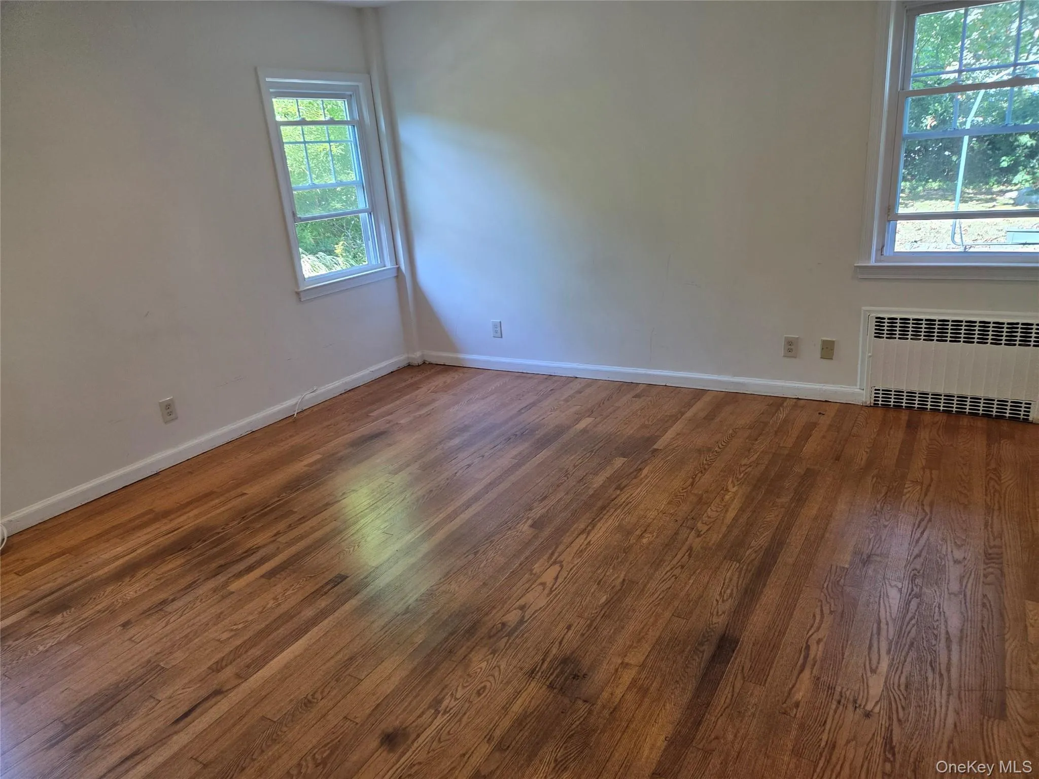 Empty room featuring radiator heating unit and wood finished floors Empty room featuring radiator heating unit and wood finished floors