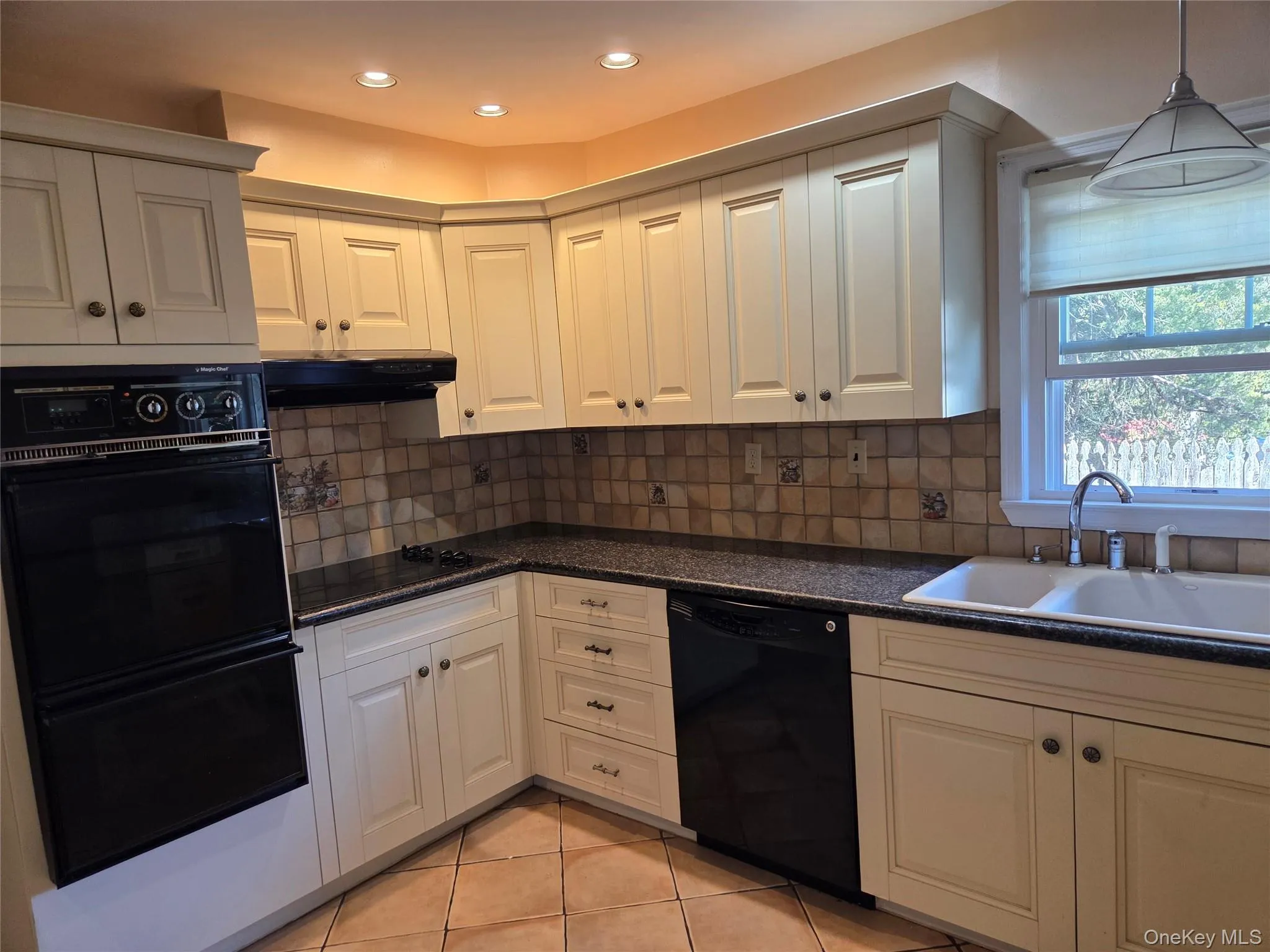 Kitchen featuring black appliances, decorative backsplash, light tile patterned floors, exhaust hood, and recessed lighting Kitchen featuring black appliances, decorative backsplash, light tile patterned floors, exhaust hood, and recessed lighting