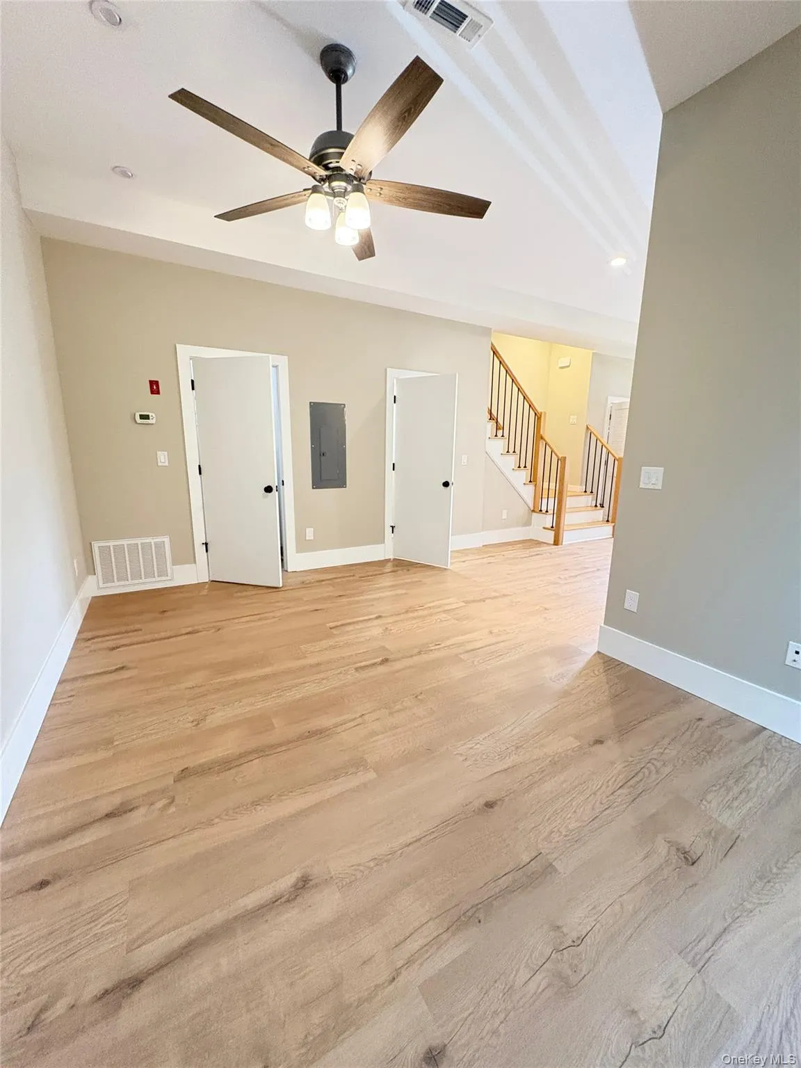 Unfurnished living room with stairway, light wood finished floors, electric panel, ceiling fan, and recessed lighting Unfurnished living room with stairway, light wood finished floors, electric panel, ceiling fan, and recessed lighting