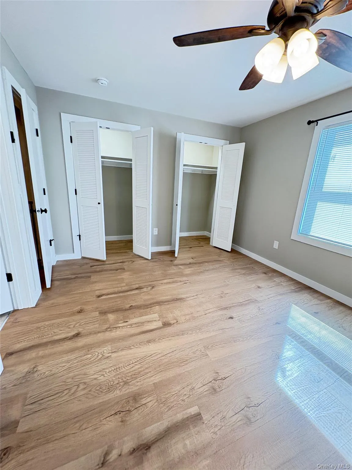 Unfurnished bedroom with two closets, light wood-style flooring, and a ceiling fan Unfurnished bedroom with two closets, light wood-style flooring, and a ceiling fan