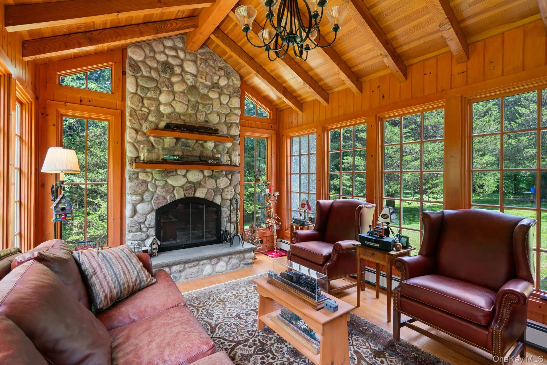 Living room with wood finished floors, a fireplace, a chandelier, baseboard heating, and wooden ceiling Living room with wood finished floors, a fireplace, a chandelier, baseboard heating, and wooden ceiling