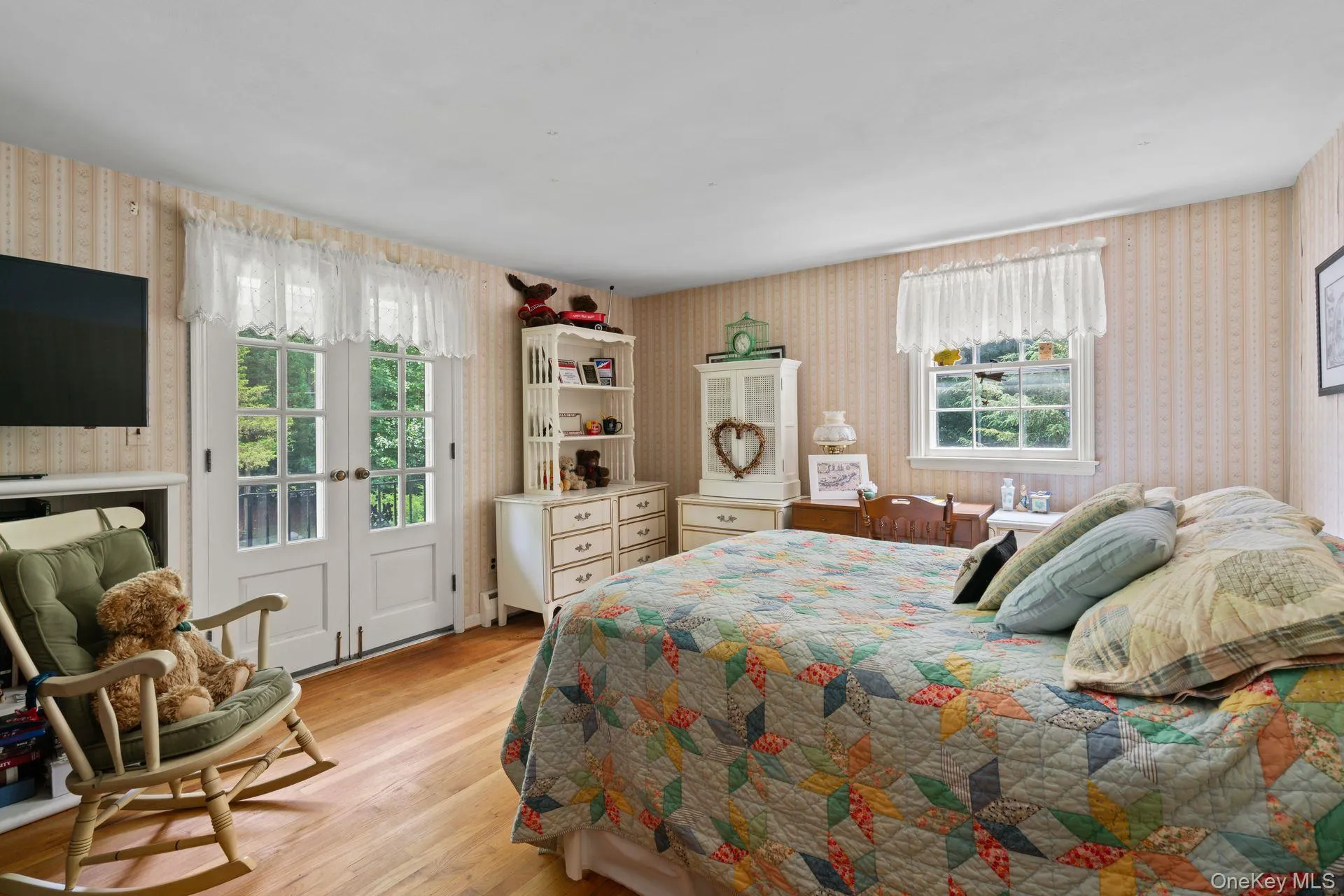 Bedroom featuring wallpapered walls, access to exterior, and light wood-style floors Bedroom featuring wallpapered walls, access to exterior, and light wood-style floors