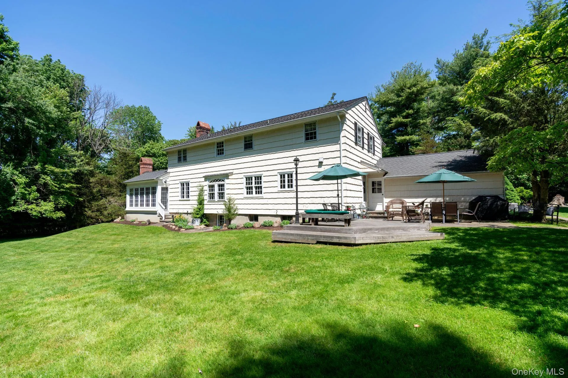 Rear view of house featuring a chimney, a lawn, and a wooden deck Rear view of house featuring a chimney, a lawn, and a wooden deck
