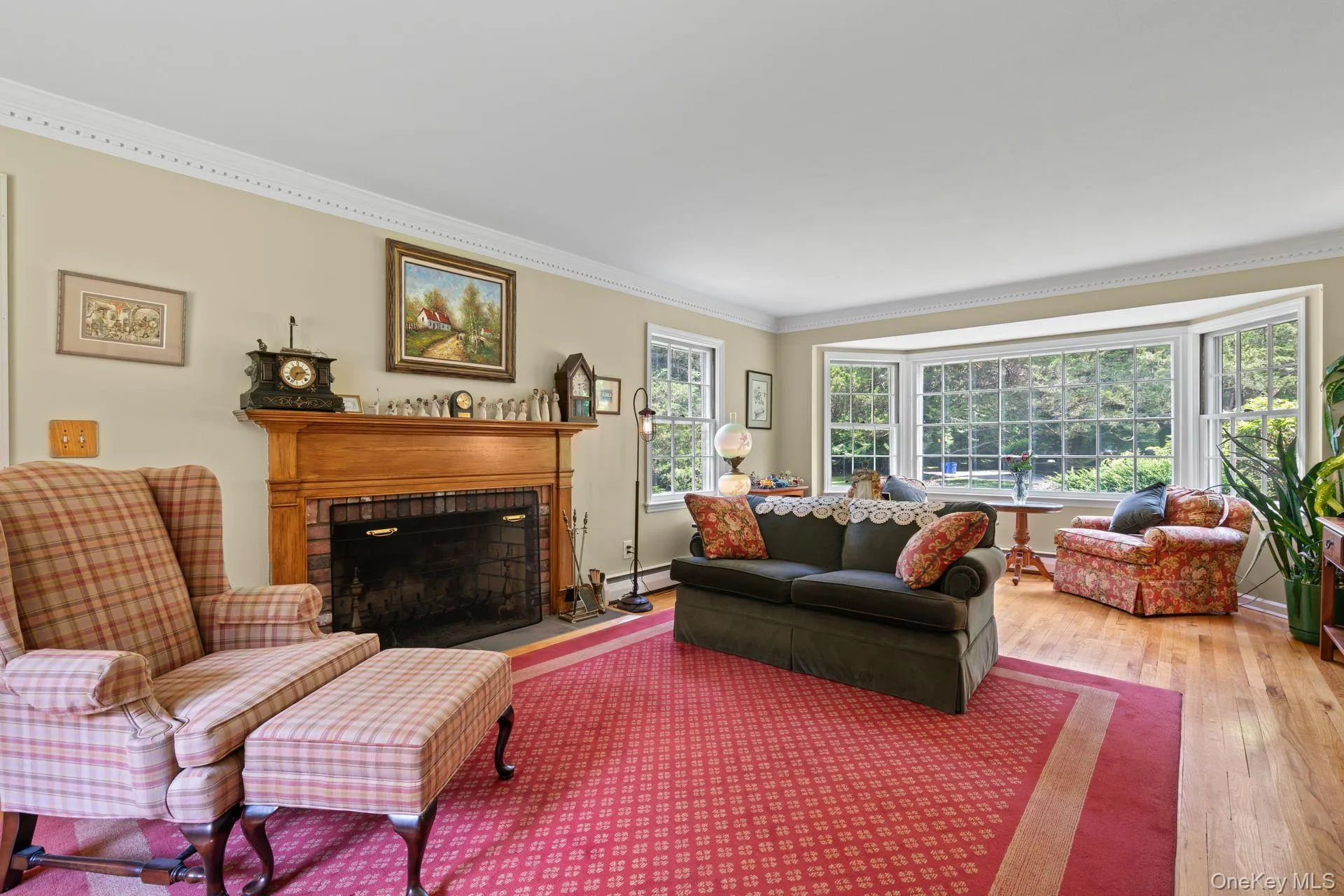 Living room featuring crown molding, a fireplace, hardwood / wood-style flooring, and a baseboard heating unit Living room featuring crown molding, a fireplace, hardwood / wood-style flooring, and a baseboard heating unit