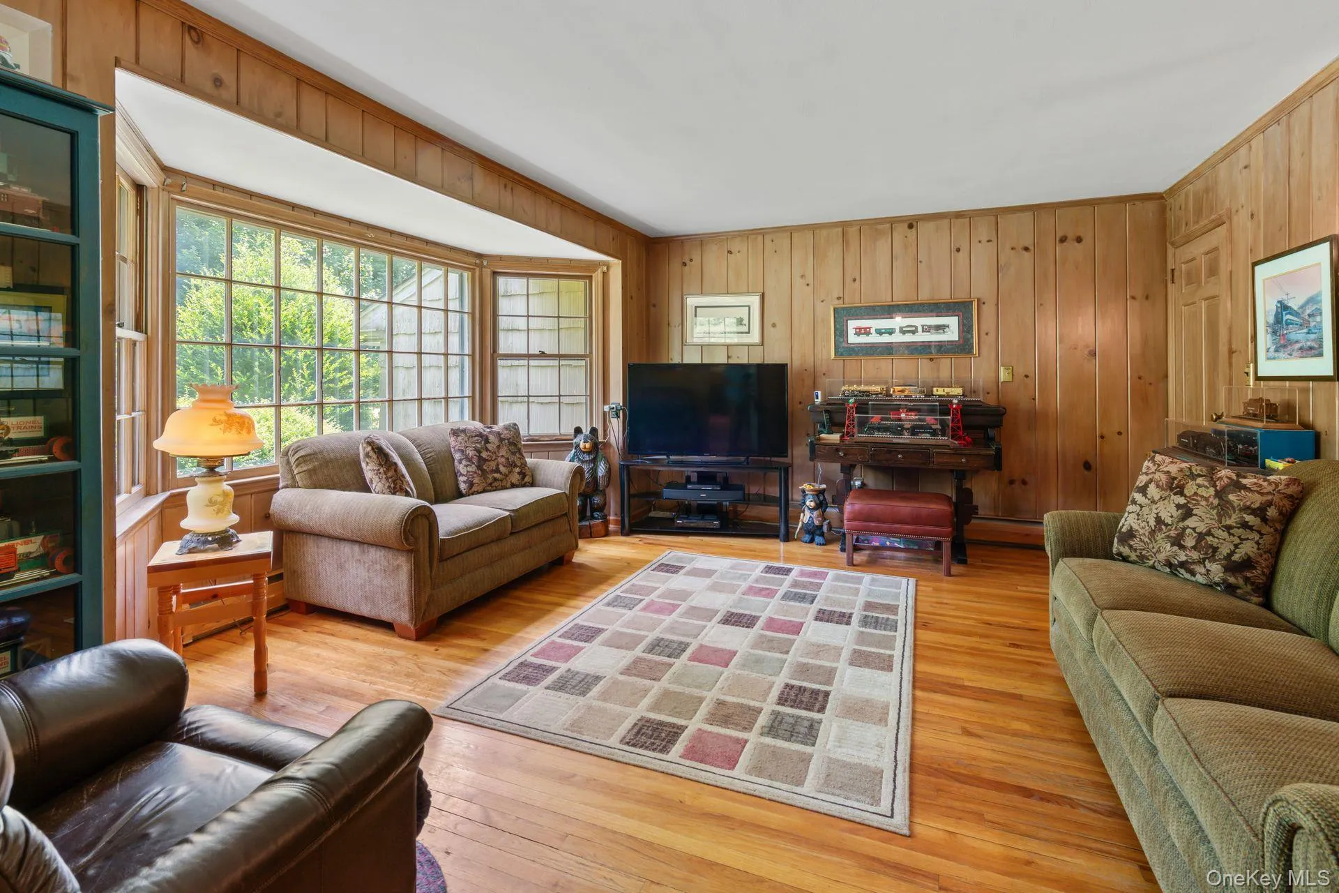 Living room with wooden walls, light wood finished floors, and baseboard heating Living room with wooden walls, light wood finished floors, and baseboard heating