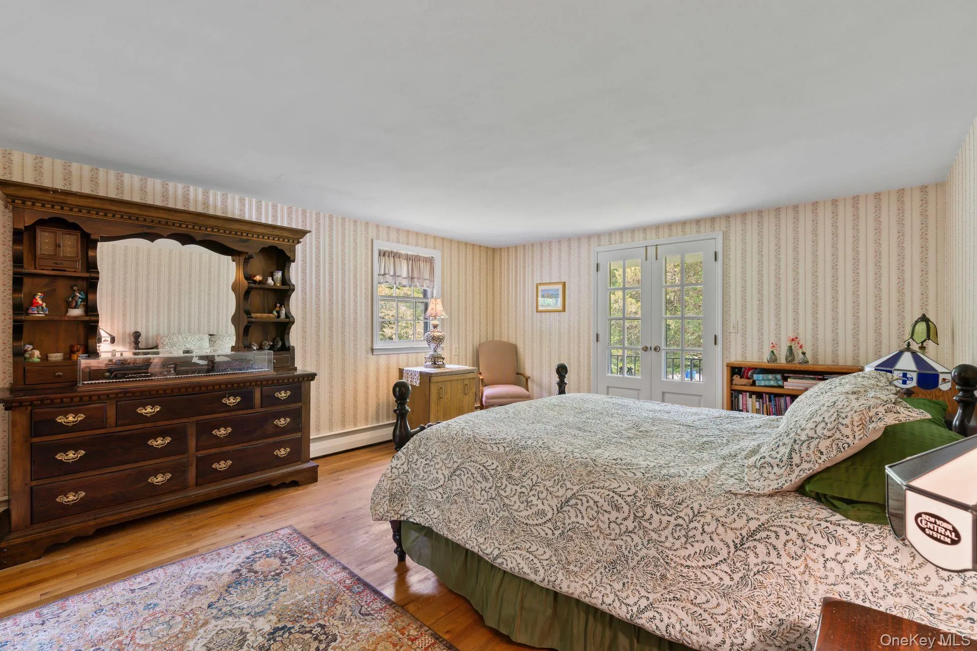 Bedroom with french doors, light wood finished floors, access to outside, a baseboard radiator, and wallpapered walls Bedroom with french doors, light wood finished floors, access to outside, a baseboard radiator, and wallpapered walls