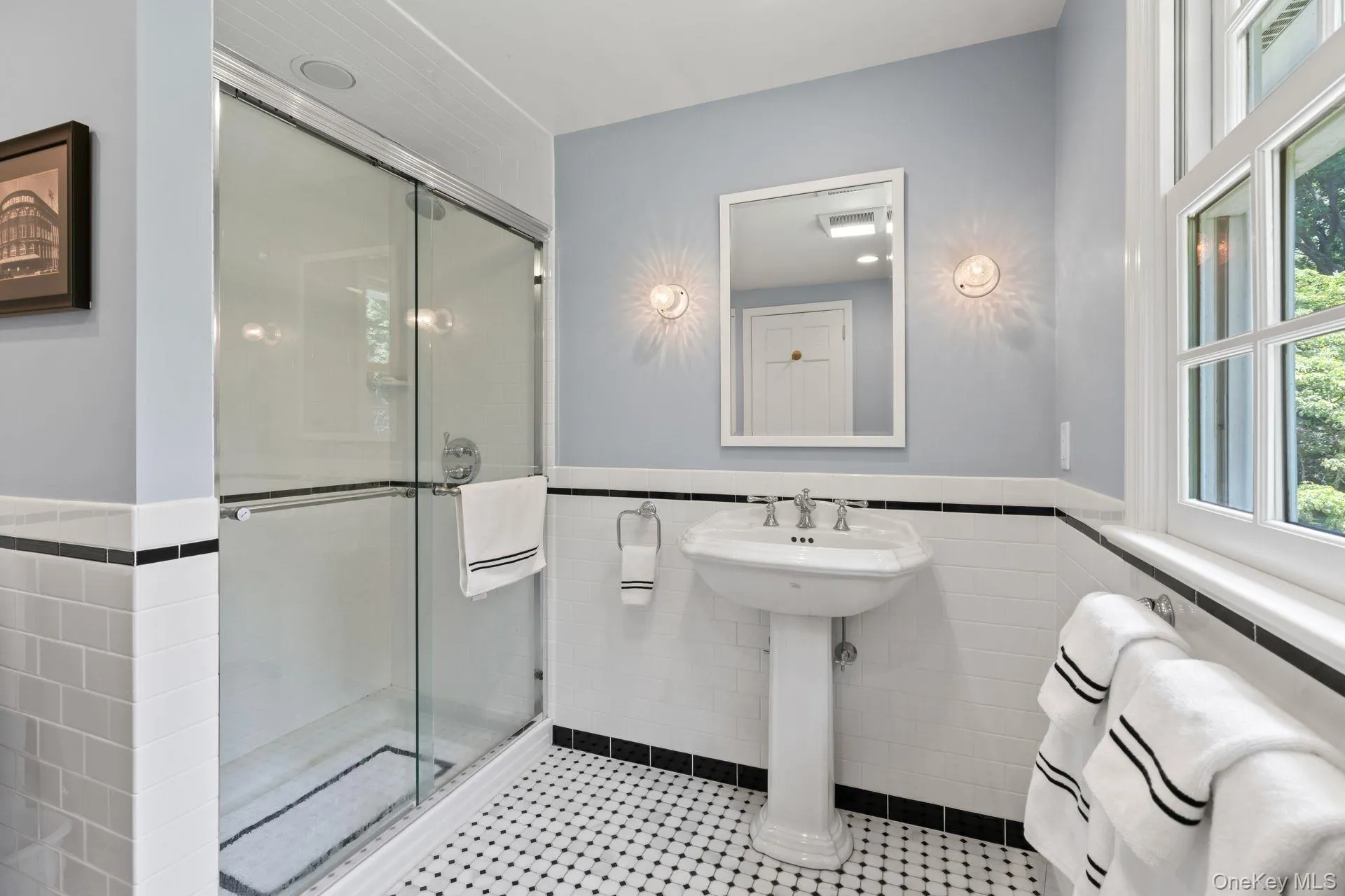 Bathroom featuring tile walls, a shower stall, a wainscoted wall, and tile patterned floors Bathroom featuring tile walls, a shower stall, a wainscoted wall, and tile patterned floors