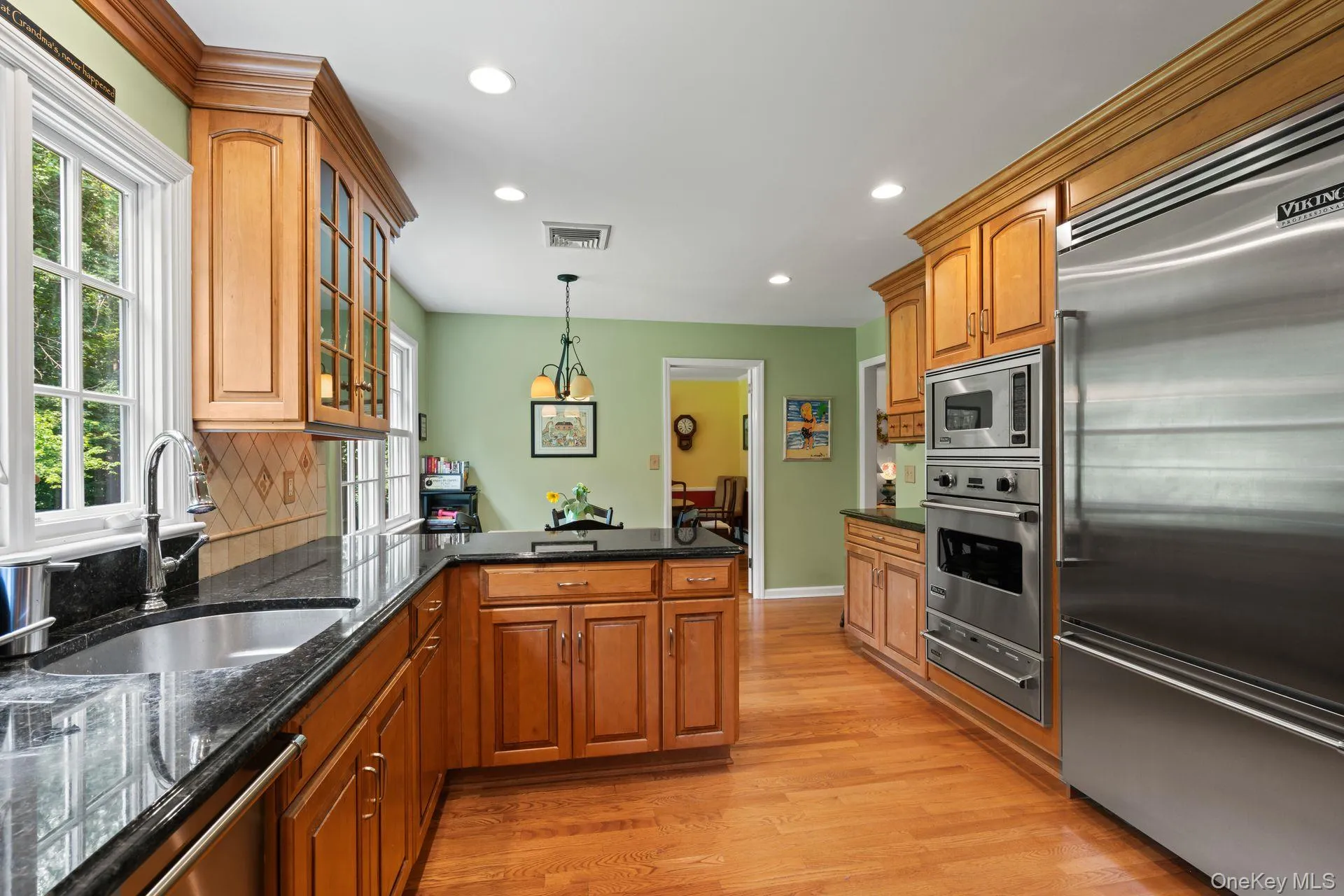 Kitchen featuring built in appliances, brown cabinets, dark stone countertops, a peninsula, and recessed lighting Kitchen featuring built in appliances, brown cabinets, dark stone countertops, a peninsula, and recessed lighting