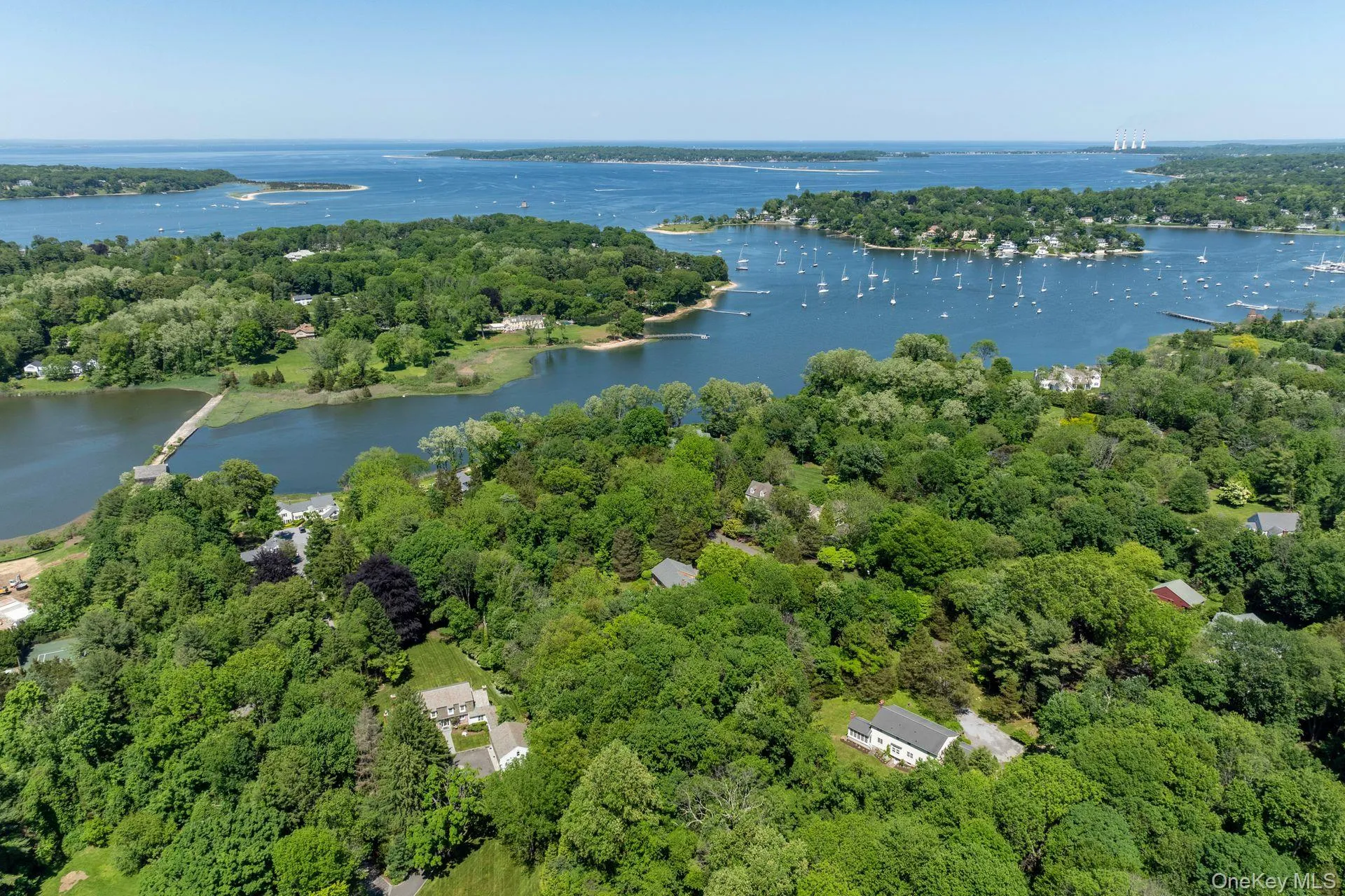 Aerial view of property and surrounding area with a nearby body of water and a heavily wooded area Aerial view of property and surrounding area with a nearby body of water and a heavily wooded area