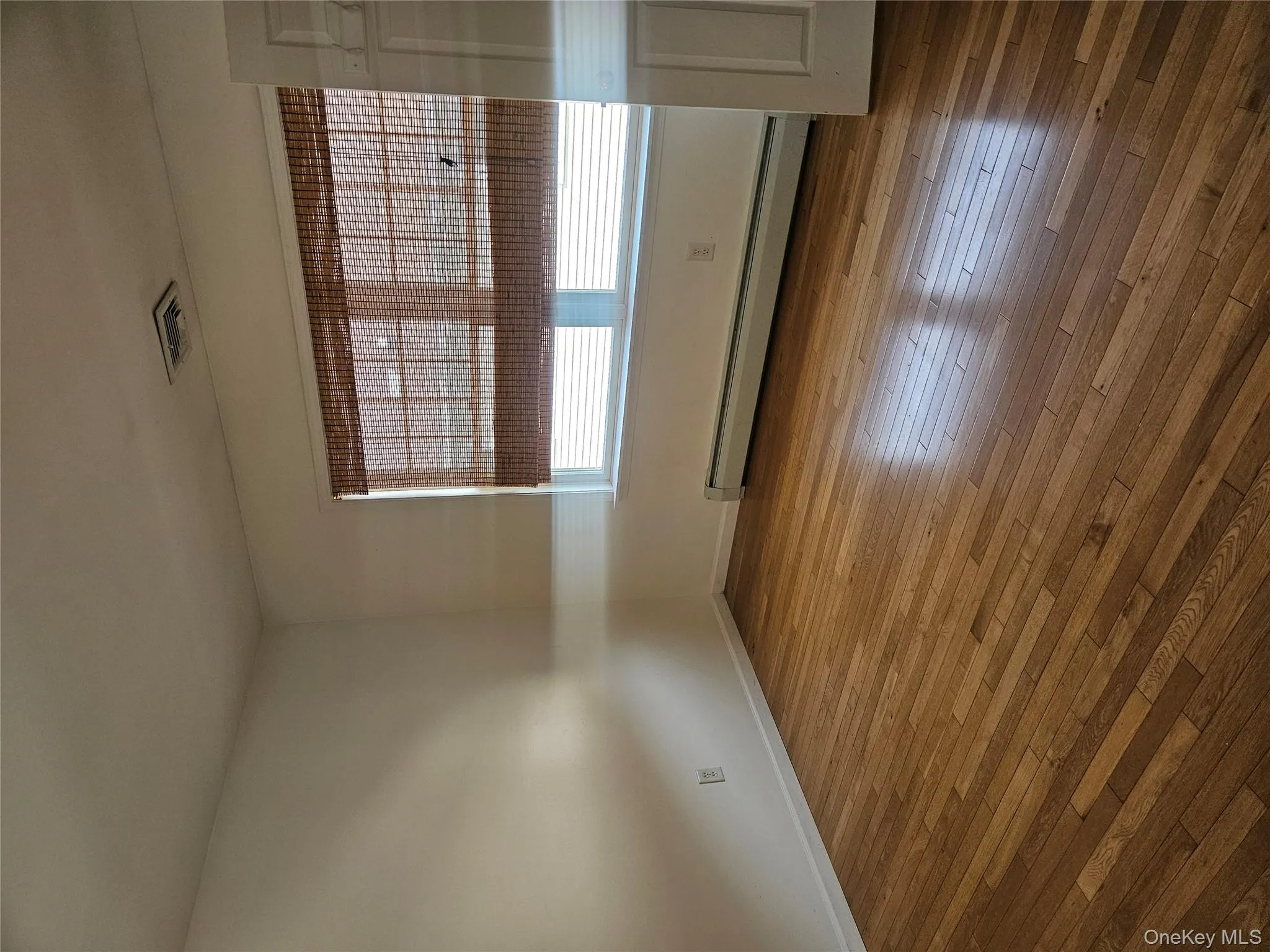 Empty room featuring baseboard heating and hardwood / wood-style floors Empty room featuring baseboard heating and hardwood / wood-style floors