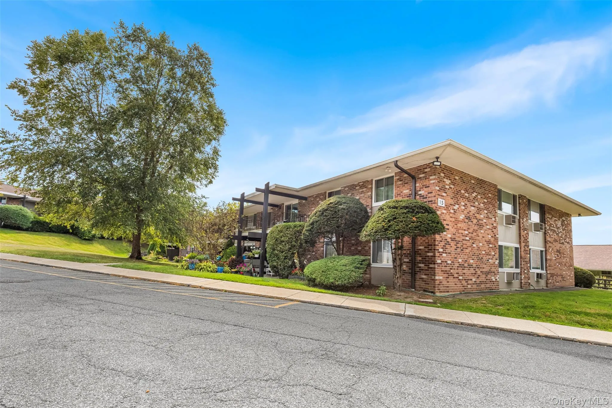 View of property exterior with brick siding, a lawn, and a balcony View of property exterior with brick siding, a lawn, and a balcony