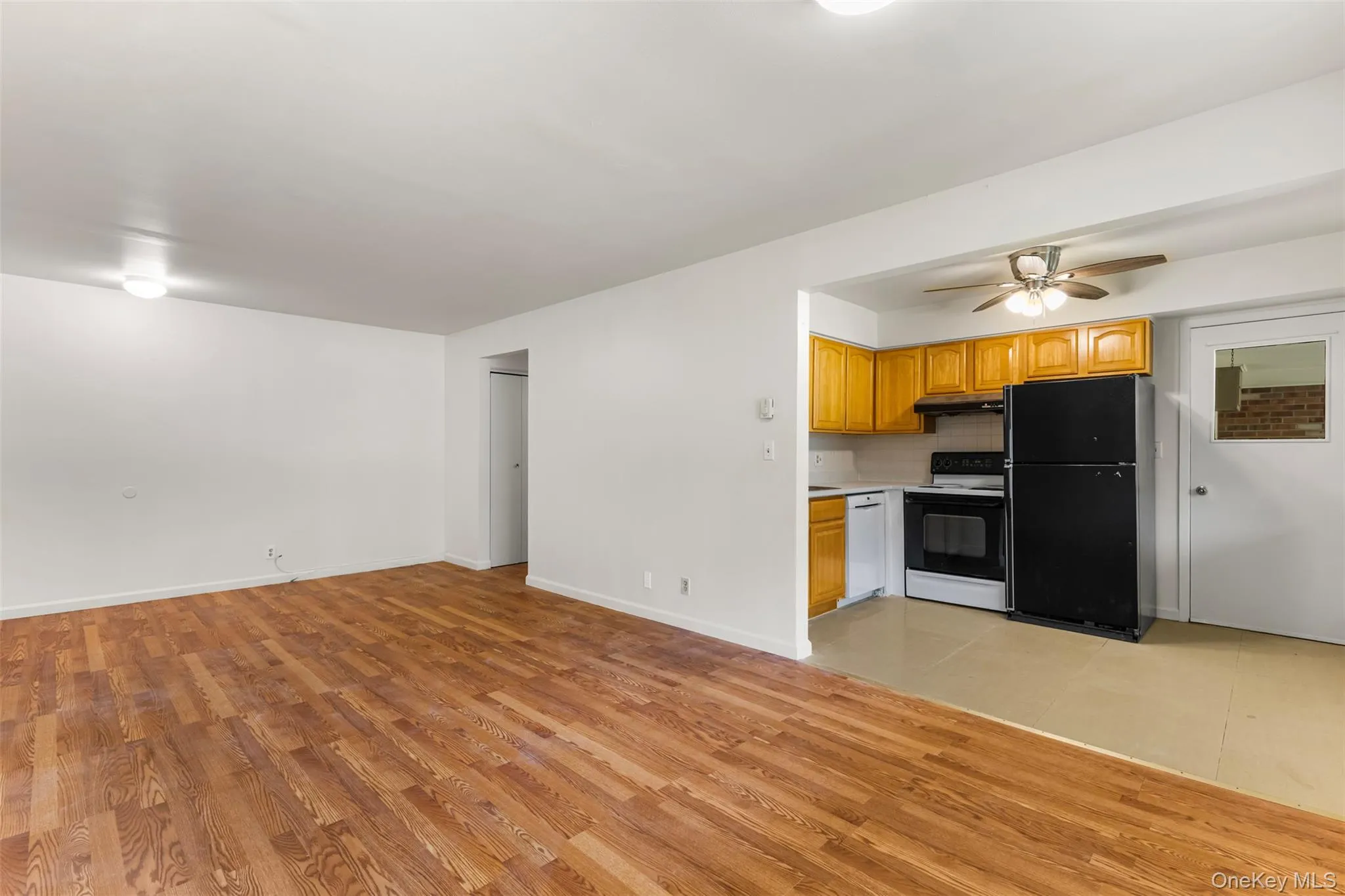 Kitchen featuring freestanding refrigerator, light countertops, electric range oven, light wood-style flooring, and open floor plan Kitchen featuring freestanding refrigerator, light countertops, electric range oven, light wood-style flooring, and open floor plan