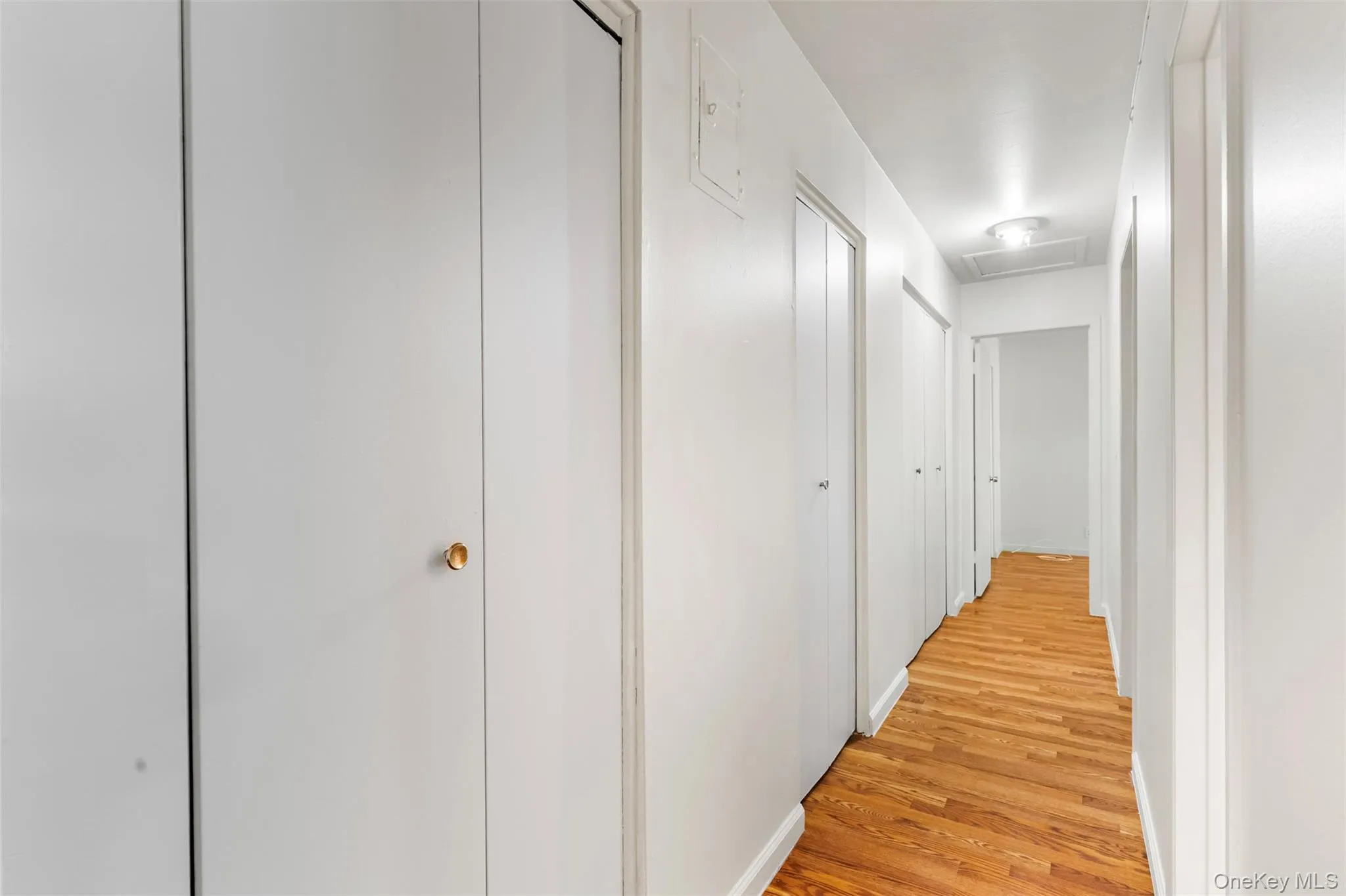Hallway with attic access and light wood finished floors Hallway with attic access and light wood finished floors