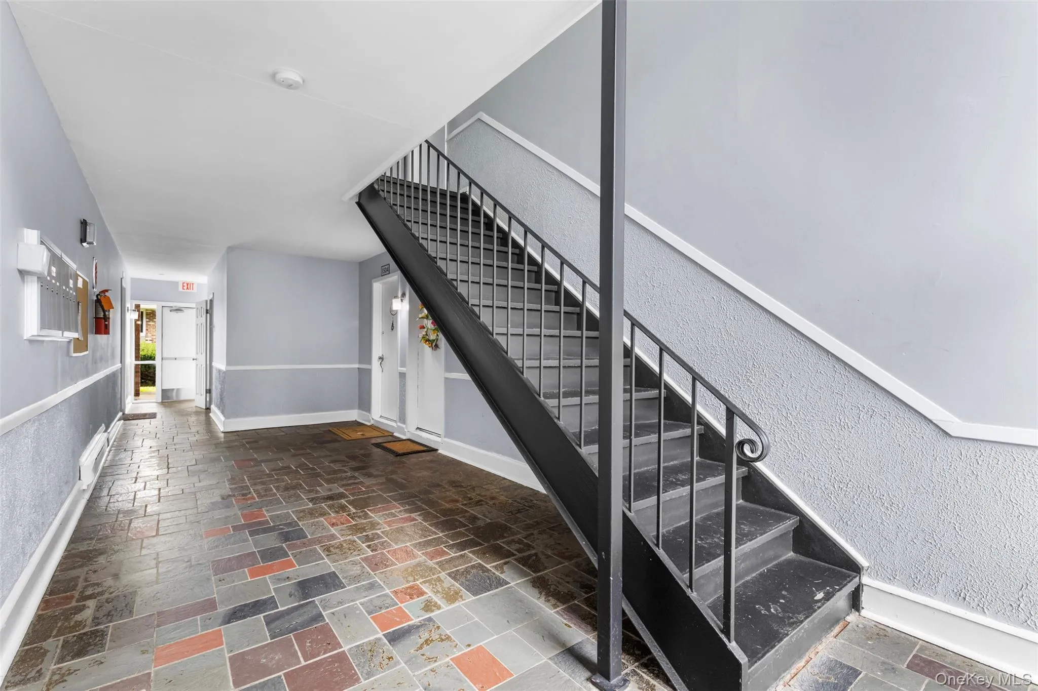 Stairway featuring stone tile floors and a textured wall Stairway featuring stone tile floors and a textured wall
