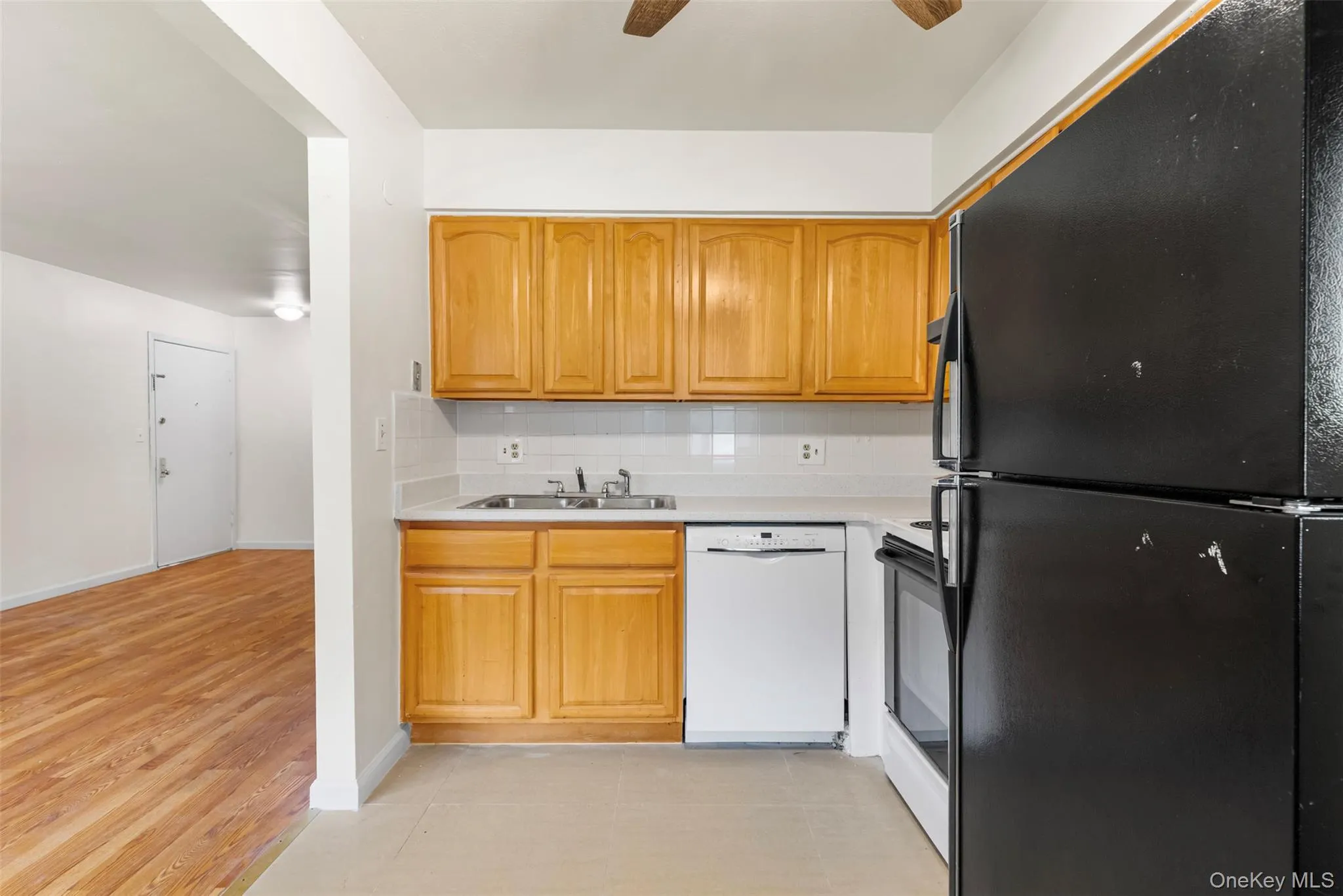 Kitchen with black appliances, light countertops, backsplash, light wood finished floors, and ceiling fan Kitchen with black appliances, light countertops, backsplash, light wood finished floors, and ceiling fan