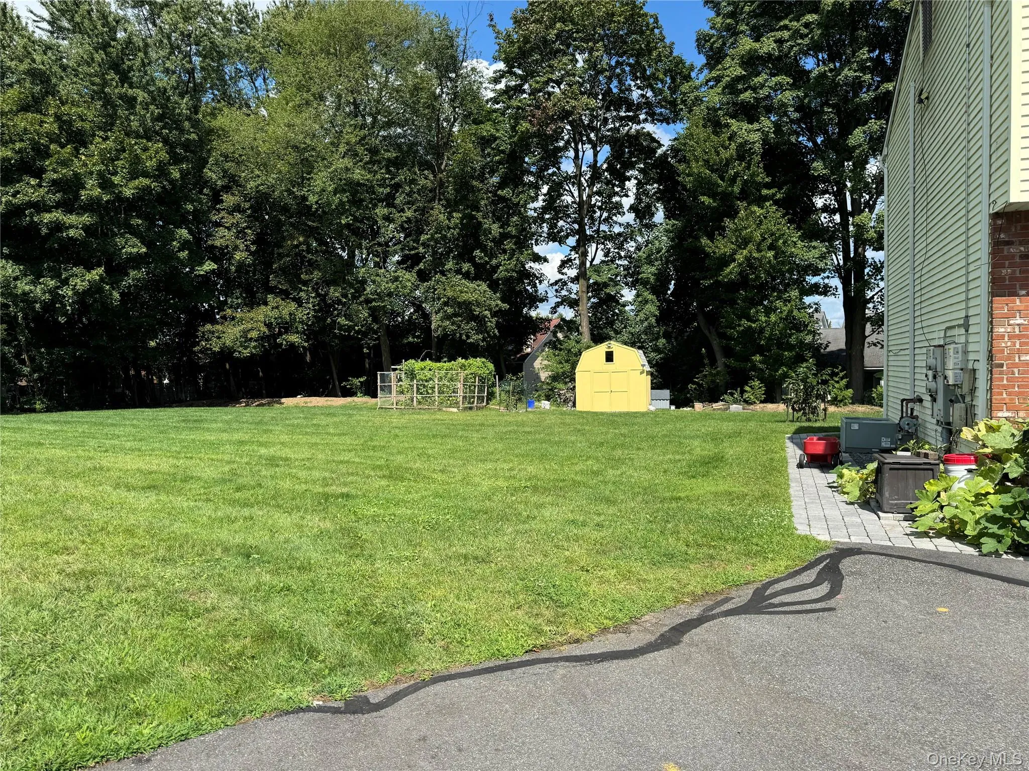 View of grassy yard featuring a storage unit and view of scattered trees View of grassy yard featuring a storage unit and view of scattered trees