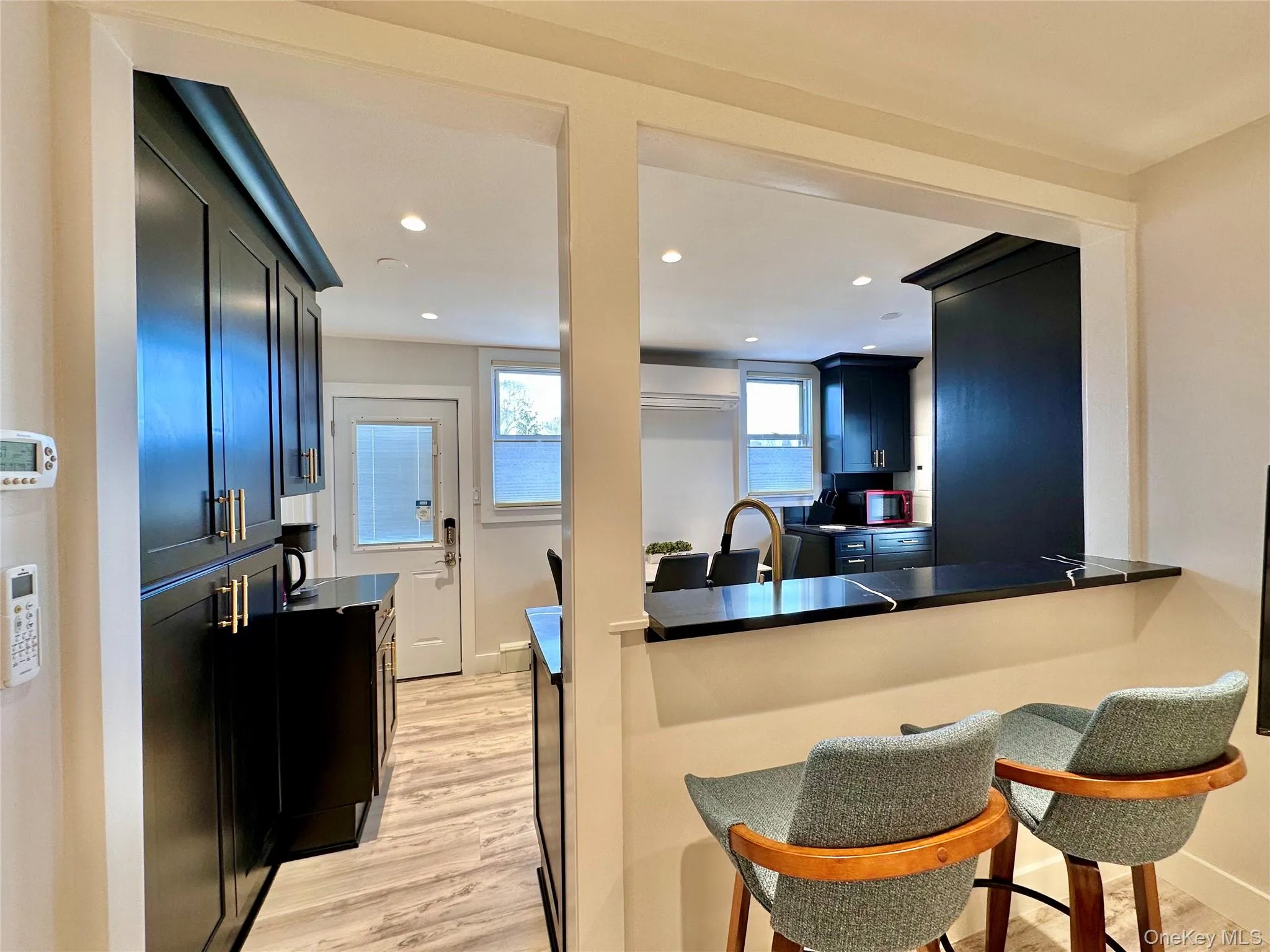 Kitchen featuring light wood-style floors, dark countertops, a breakfast bar, recessed lighting, and dark cabinetry Kitchen featuring light wood-style floors, dark countertops, a breakfast bar, recessed lighting, and dark cabinetry
