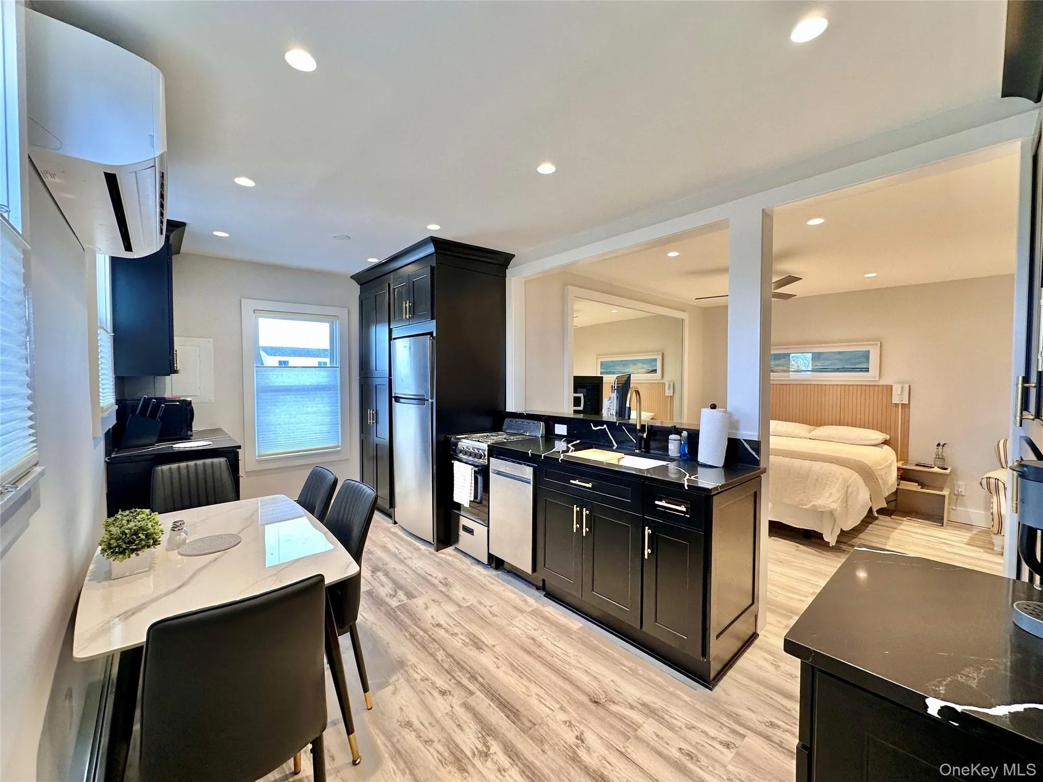 Kitchen featuring dark cabinets, stainless steel appliances, light wood-style floors, open floor plan, and recessed lighting Kitchen featuring dark cabinets, stainless steel appliances, light wood-style floors, open floor plan, and recessed lighting