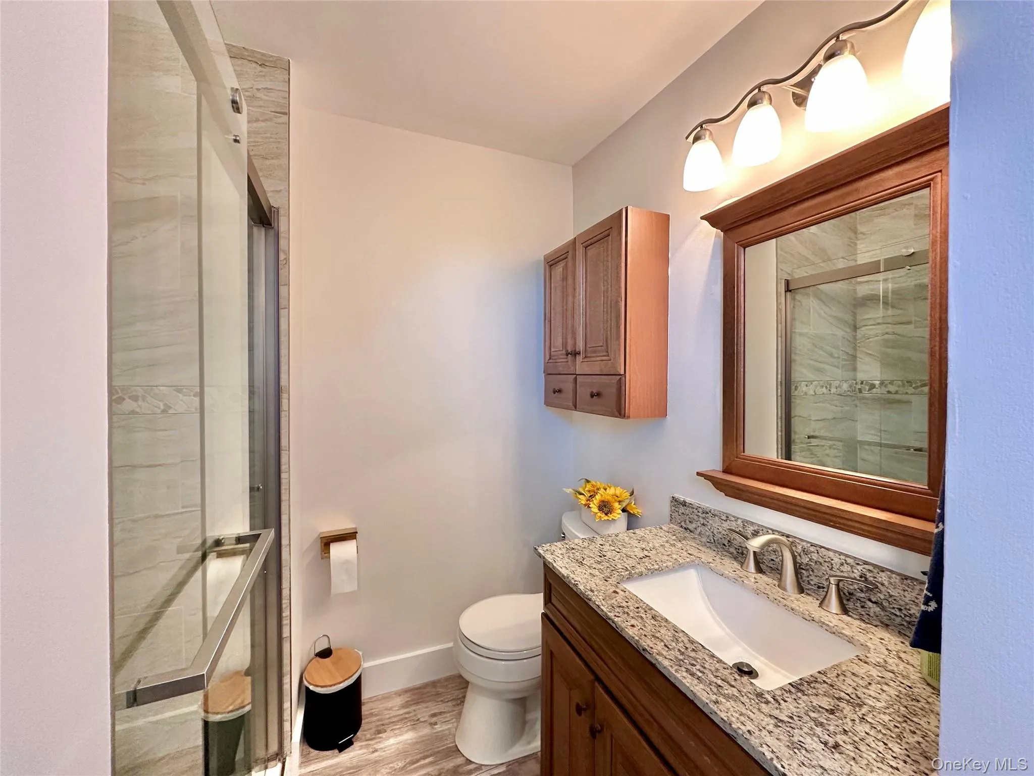 Full bathroom featuring vanity, a stall shower, and light wood finished floors Full bathroom featuring vanity, a stall shower, and light wood finished floors
