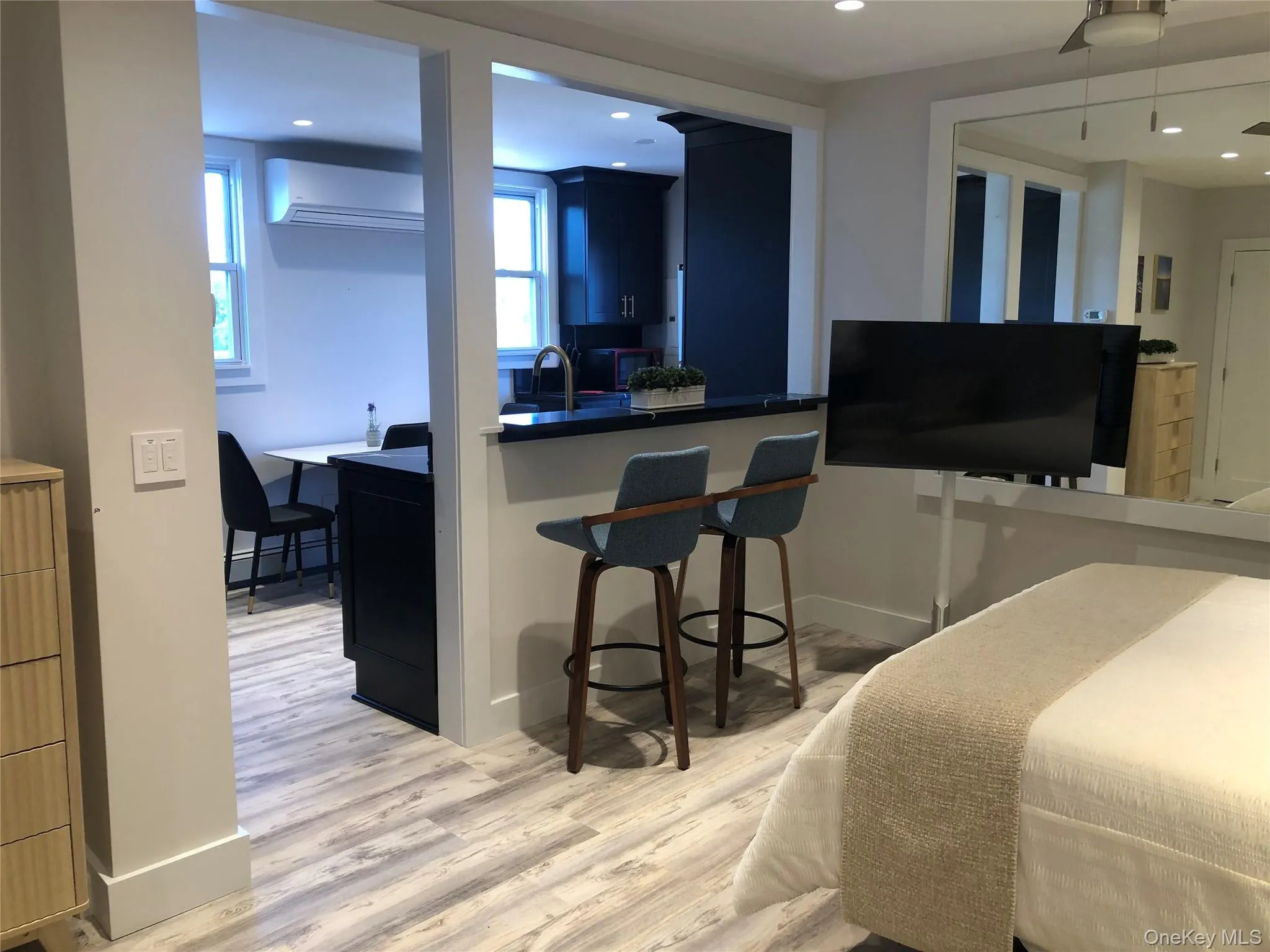 Kitchen with a kitchen breakfast bar, light wood finished floors, a wall mounted air conditioner, dark countertops, and recessed lighting Kitchen with a kitchen breakfast bar, light wood finished floors, a wall mounted air conditioner, dark countertops, and recessed lighting