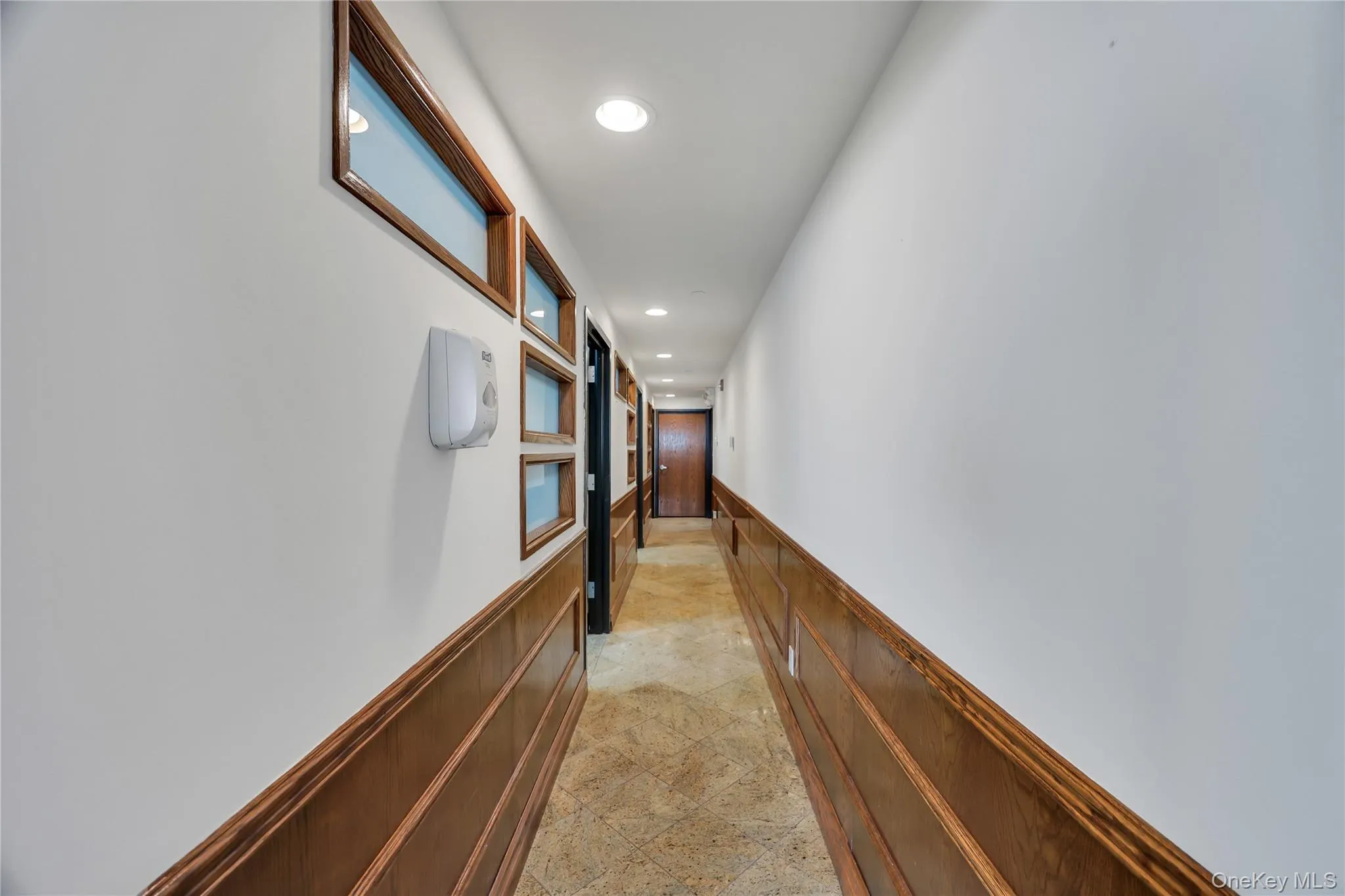 Corridor with a wainscoted wall, recessed lighting, and a decorative wall Corridor with a wainscoted wall, recessed lighting, and a decorative wall