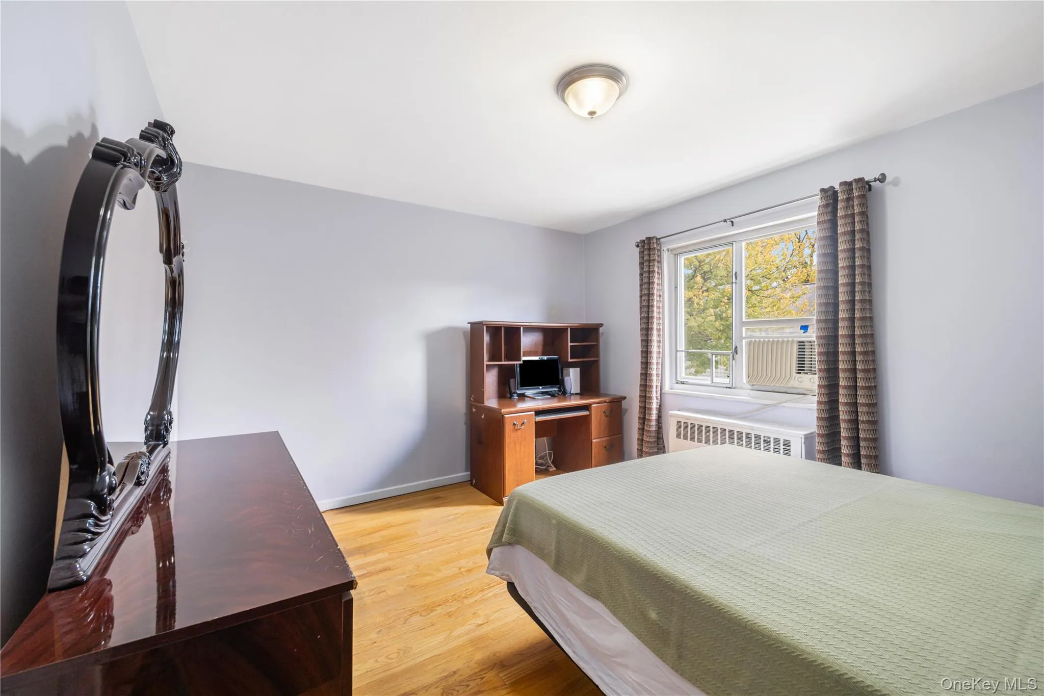 Bedroom featuring light wood-style flooring, radiator heating unit, and cooling unit Bedroom featuring light wood-style flooring, radiator heating unit, and cooling unit