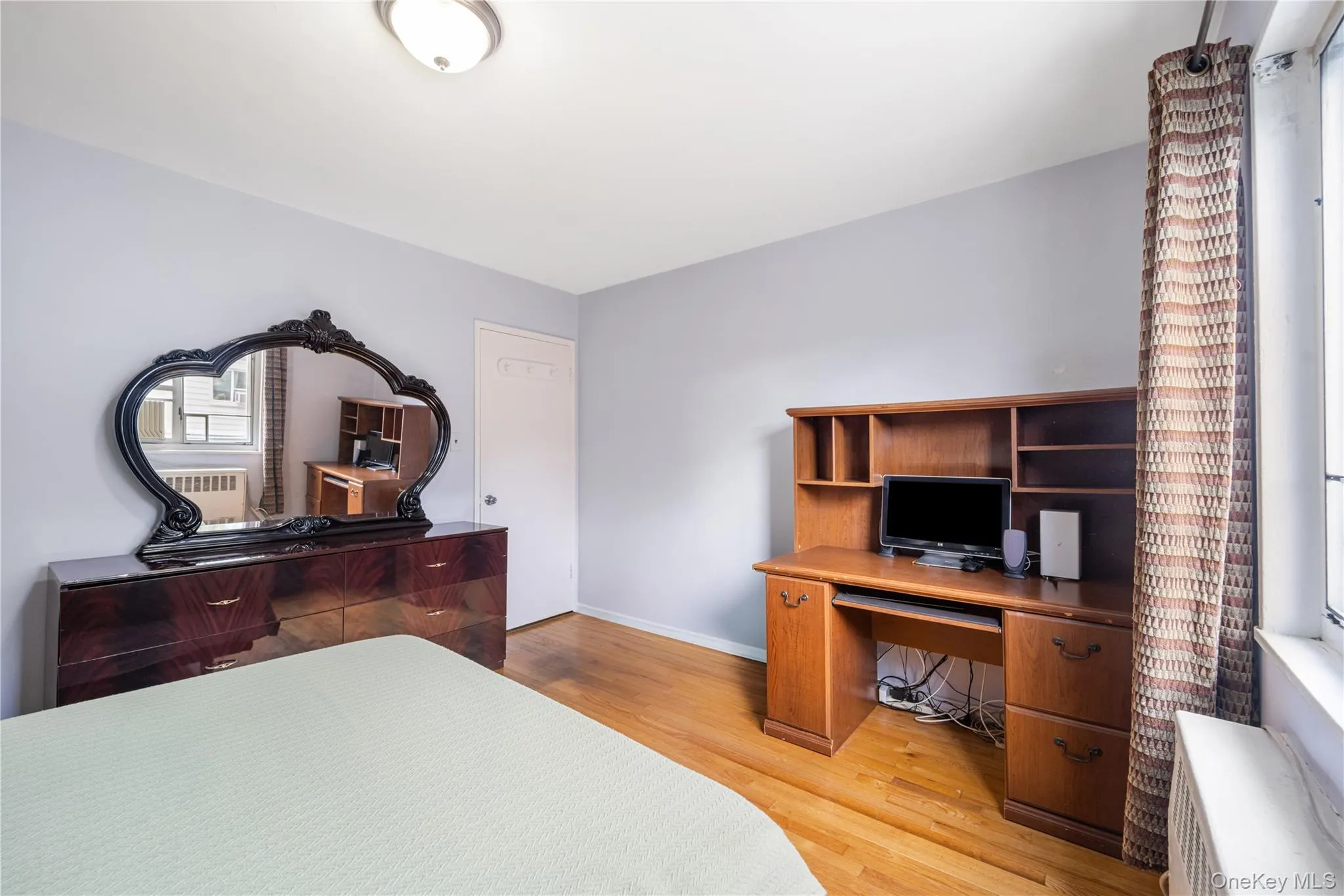 Bedroom featuring a desk, light wood-style floors, and radiator Bedroom featuring a desk, light wood-style floors, and radiator