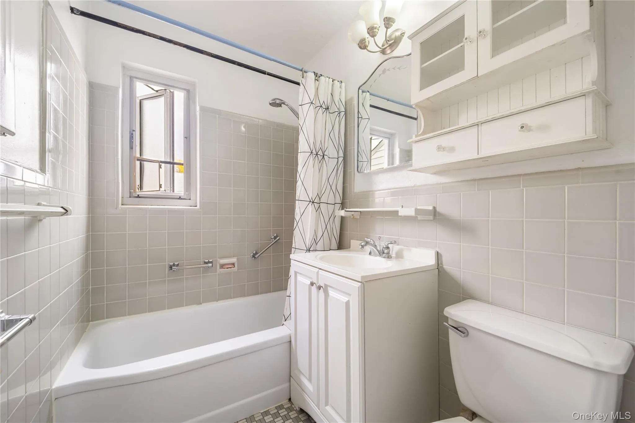 Bathroom featuring shower / tub combo with curtain, tile walls, vanity, and a chandelier Bathroom featuring shower / tub combo with curtain, tile walls, vanity, and a chandelier