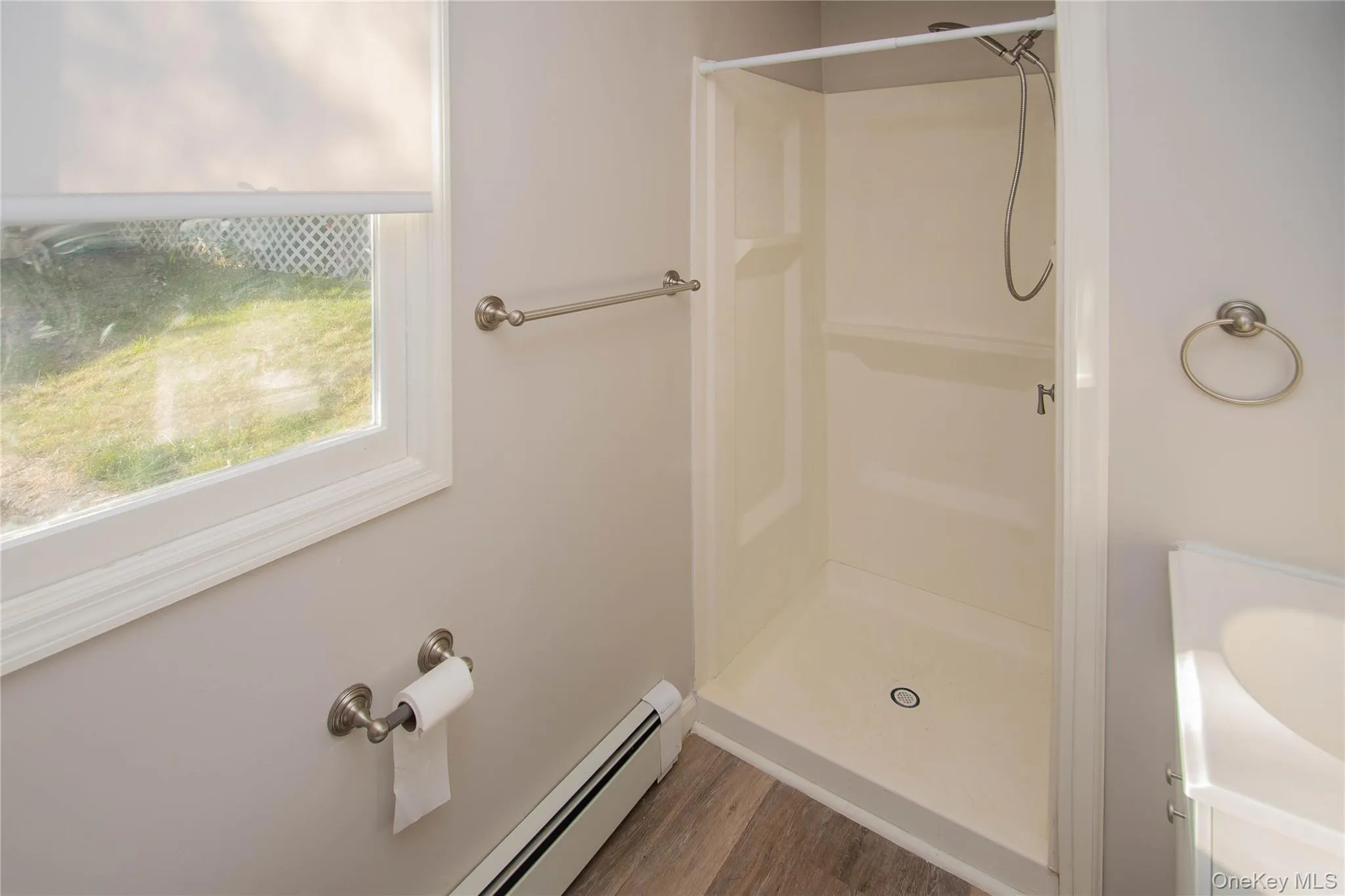 Full bath featuring baseboard heating, wood finished floors, and a stall shower, with new GFI outlets Full bath featuring baseboard heating, wood finished floors, and a stall shower, with new GFI outlets