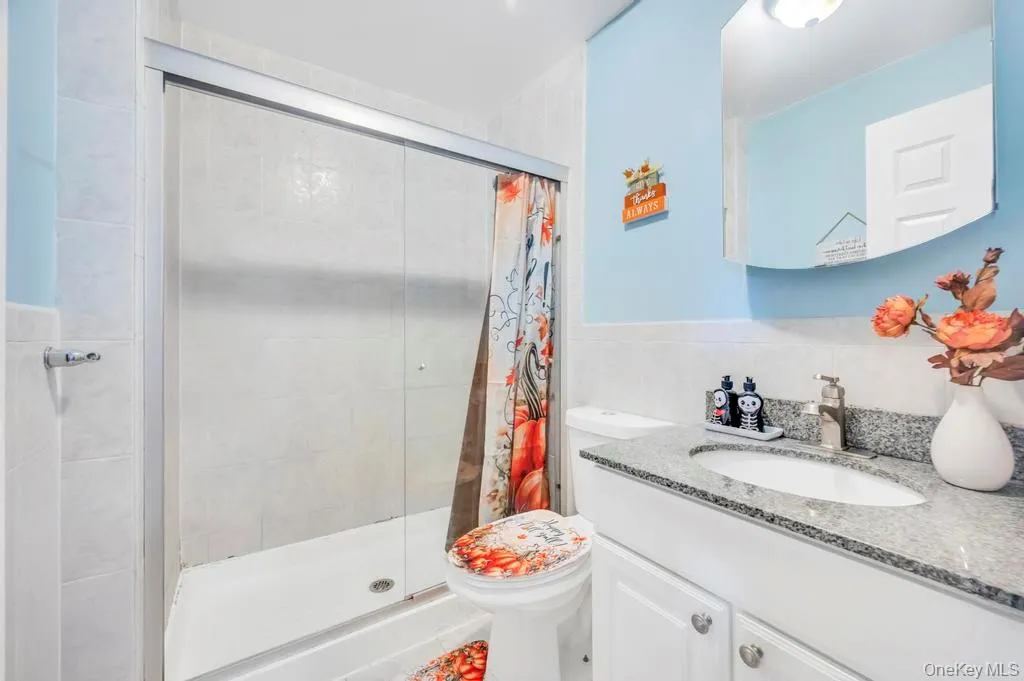 Full bath with a shower stall, vanity, and tile walls Full bath with a shower stall, vanity, and tile walls