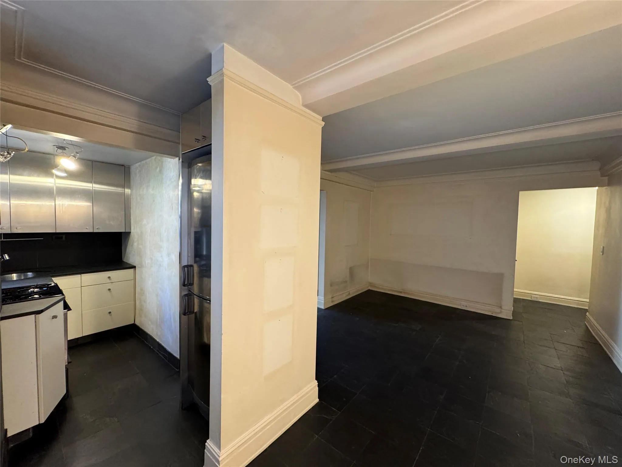 Kitchen featuring dark countertops, crown molding, freestanding refrigerator, and white cabinets Kitchen featuring dark countertops, crown molding, freestanding refrigerator, and white cabinets