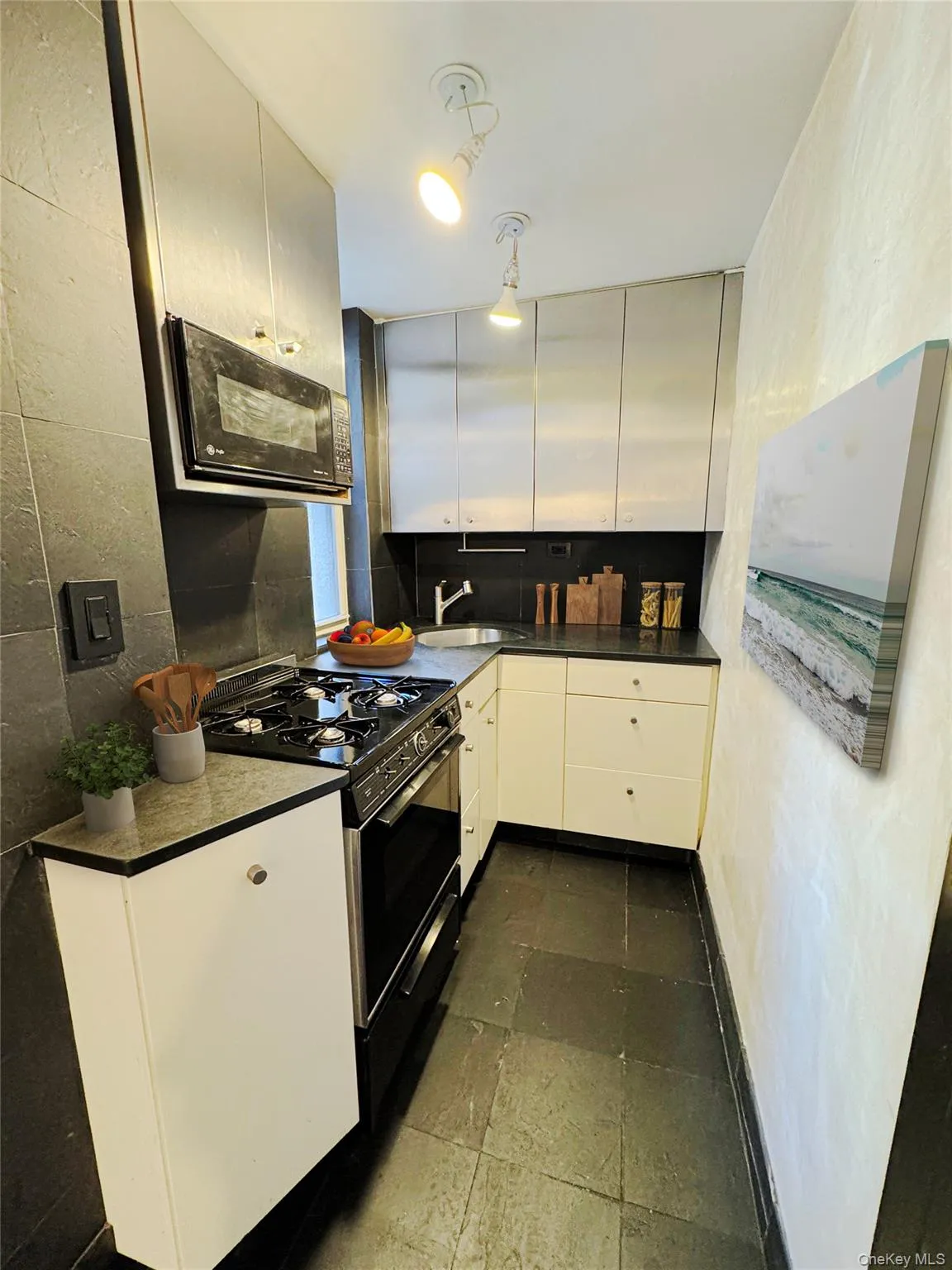 Kitchen with black appliances, white cabinets, backsplash, and a textured wall Kitchen with black appliances, white cabinets, backsplash, and a textured wall