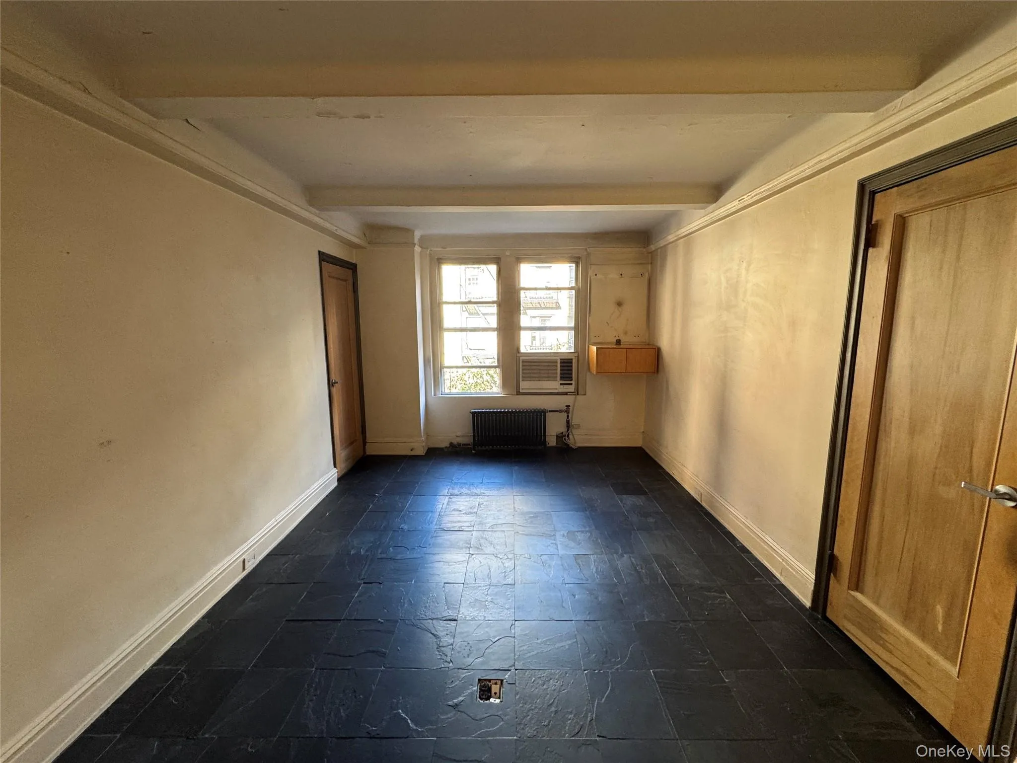 Unfurnished room featuring radiator heating unit and beam ceiling Unfurnished room featuring radiator heating unit and beam ceiling