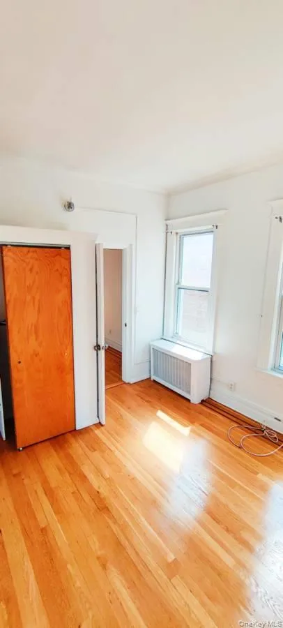 Unfurnished bedroom featuring radiator and light wood-style floors Unfurnished bedroom featuring radiator and light wood-style floors