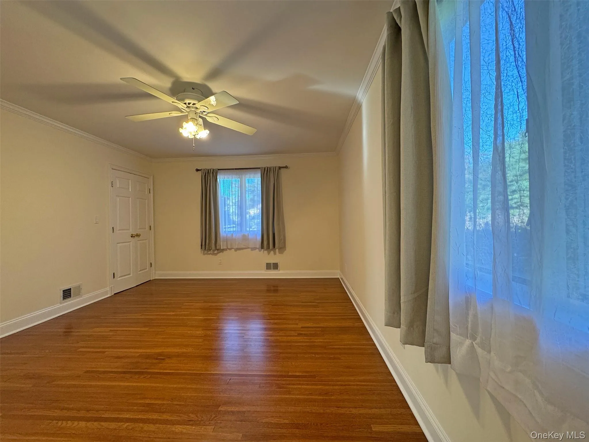 Spare room featuring wood finished floors, crown molding, and ceiling fan Spare room featuring wood finished floors, crown molding, and ceiling fan