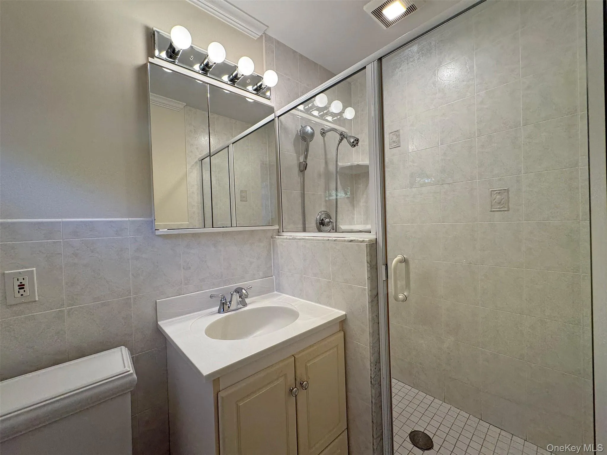 Full bath with a stall shower, vanity, and tile walls Full bath with a stall shower, vanity, and tile walls