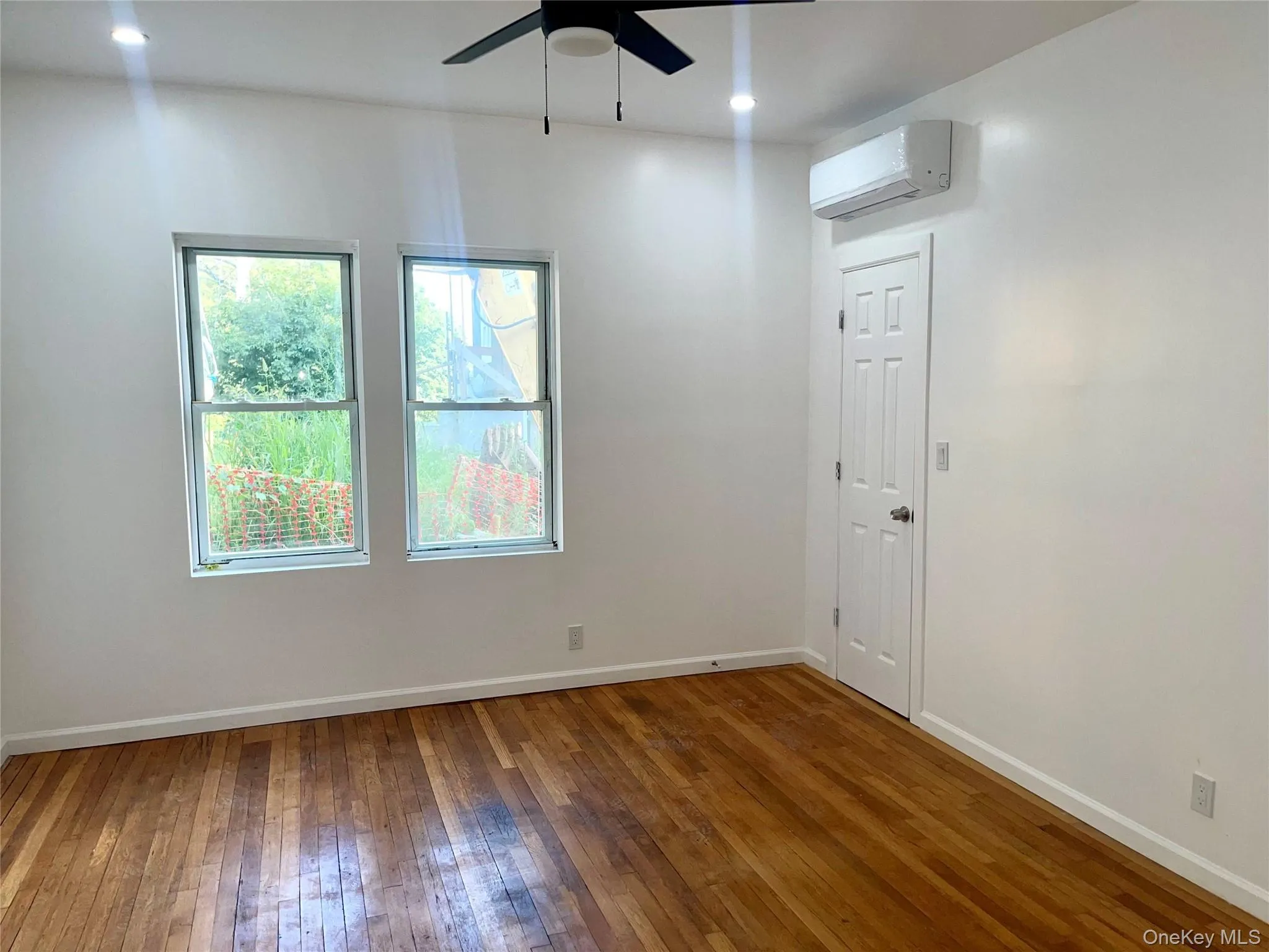 Spare room featuring hardwood / wood-style flooring, a ceiling fan, a wall mounted air conditioner, and recessed lighting Spare room featuring hardwood / wood-style flooring, a ceiling fan, a wall mounted air conditioner, and recessed lighting