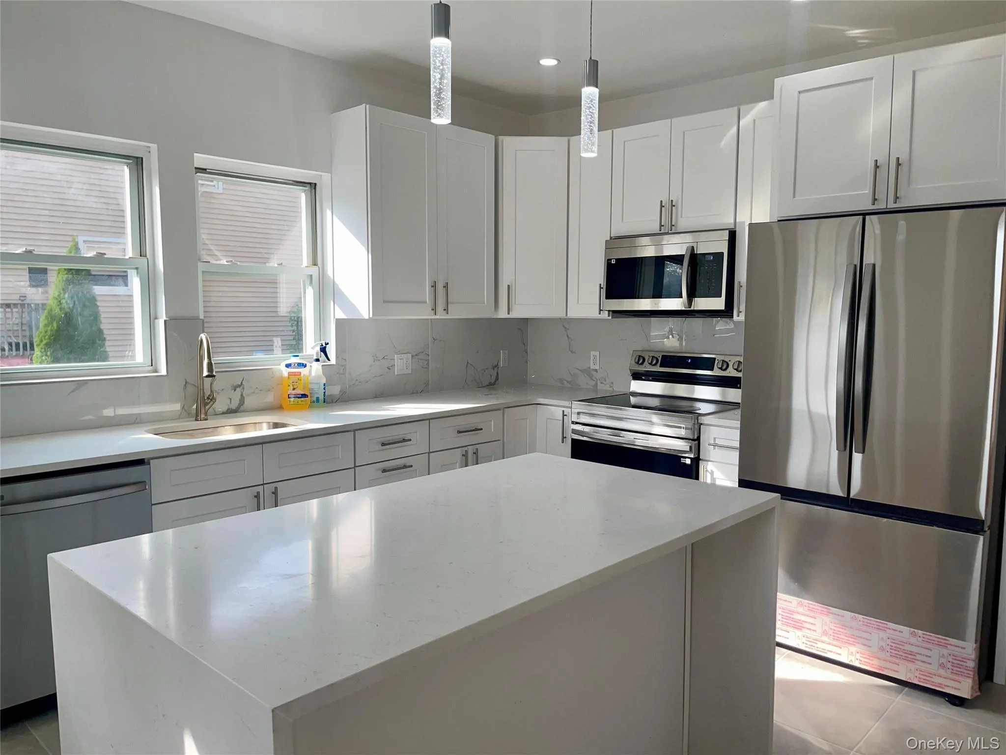 Kitchen featuring stainless steel appliances, light stone countertops, a kitchen island, decorative backsplash, and recessed lighting Kitchen featuring stainless steel appliances, light stone countertops, a kitchen island, decorative backsplash, and recessed lighting