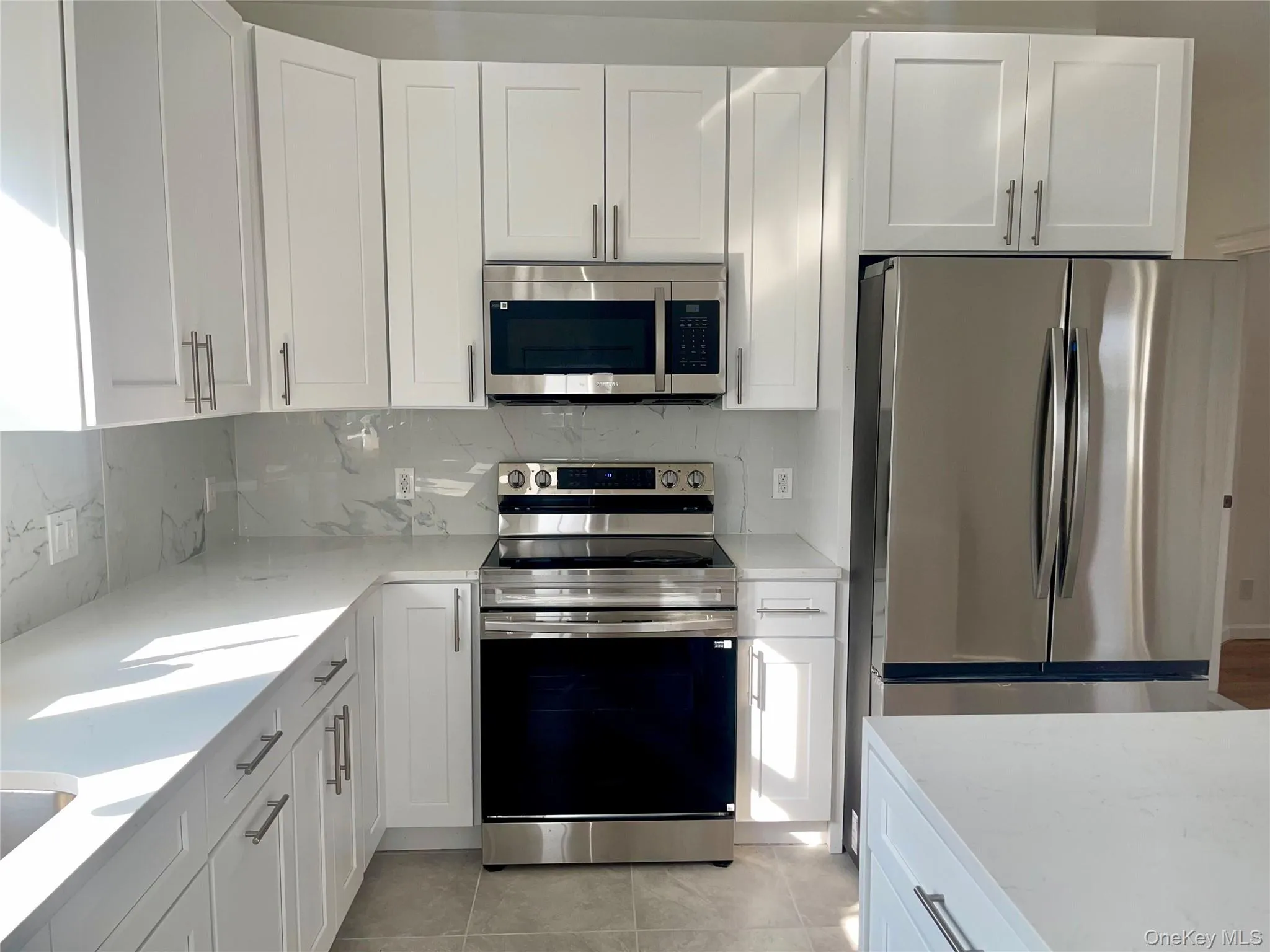 Kitchen featuring appliances with stainless steel finishes, white cabinetry, and tasteful backsplash Kitchen featuring appliances with stainless steel finishes, white cabinetry, and tasteful backsplash