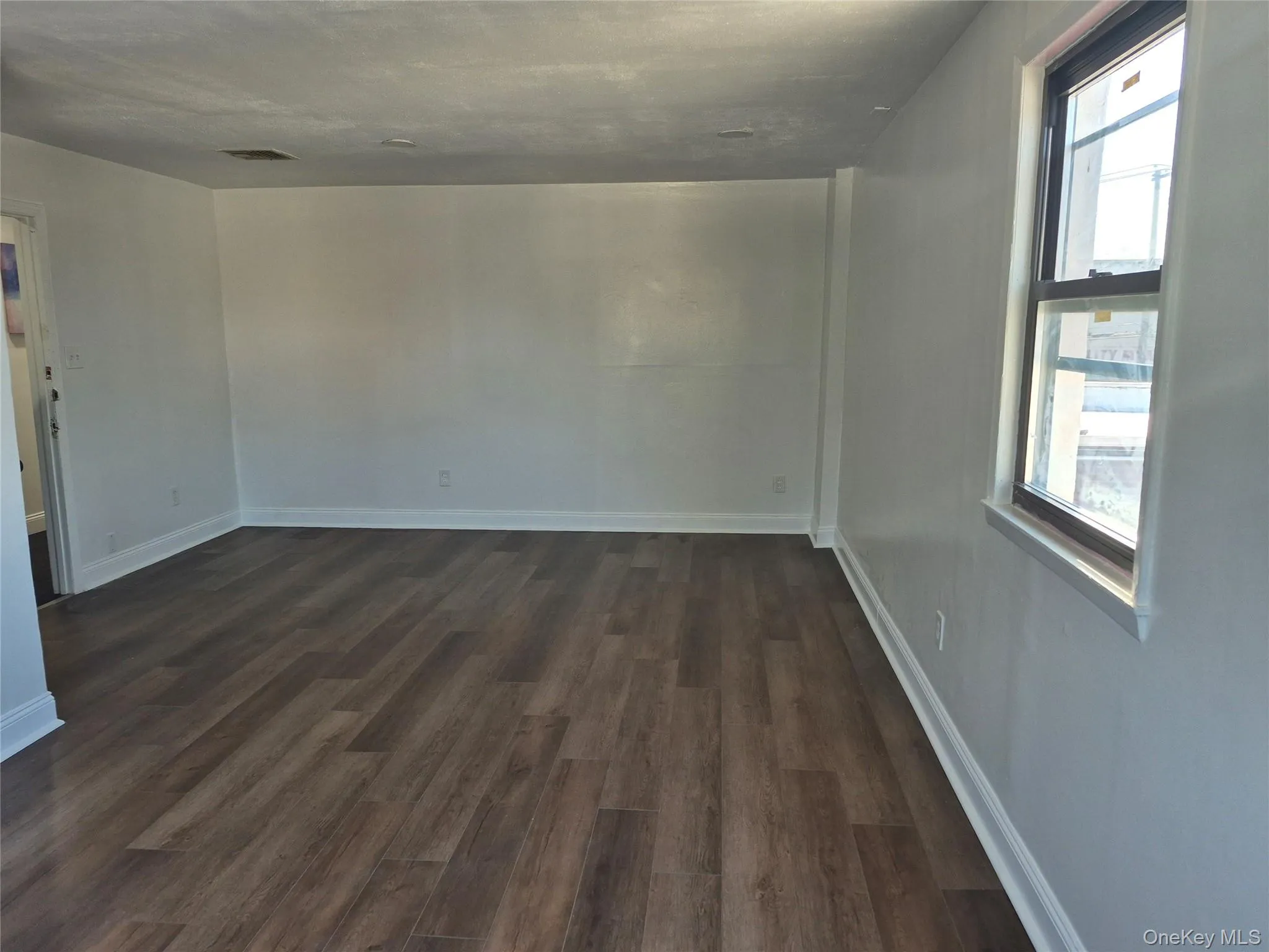 Spare room with dark wood finished floors and baseboards Spare room with dark wood finished floors and baseboards