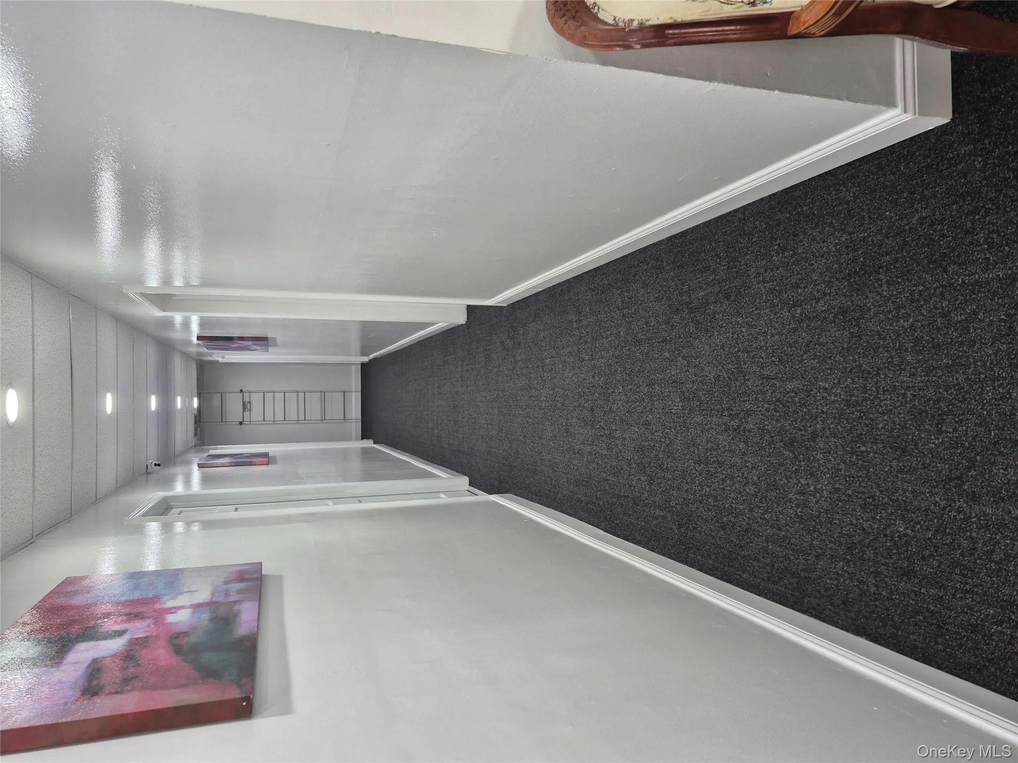 Corridor featuring baseboards and dark carpet Corridor featuring baseboards and dark carpet